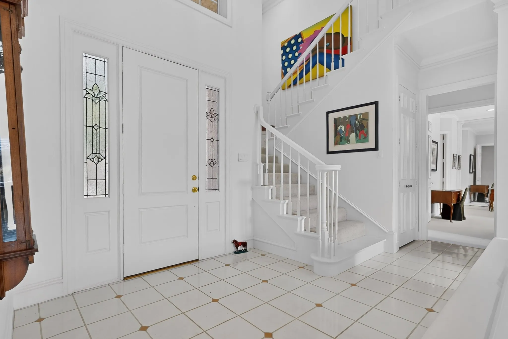 Entryway featuring a white paneled door with decorative sidelights, a white staircase with carpeted treads, and tiled flooring