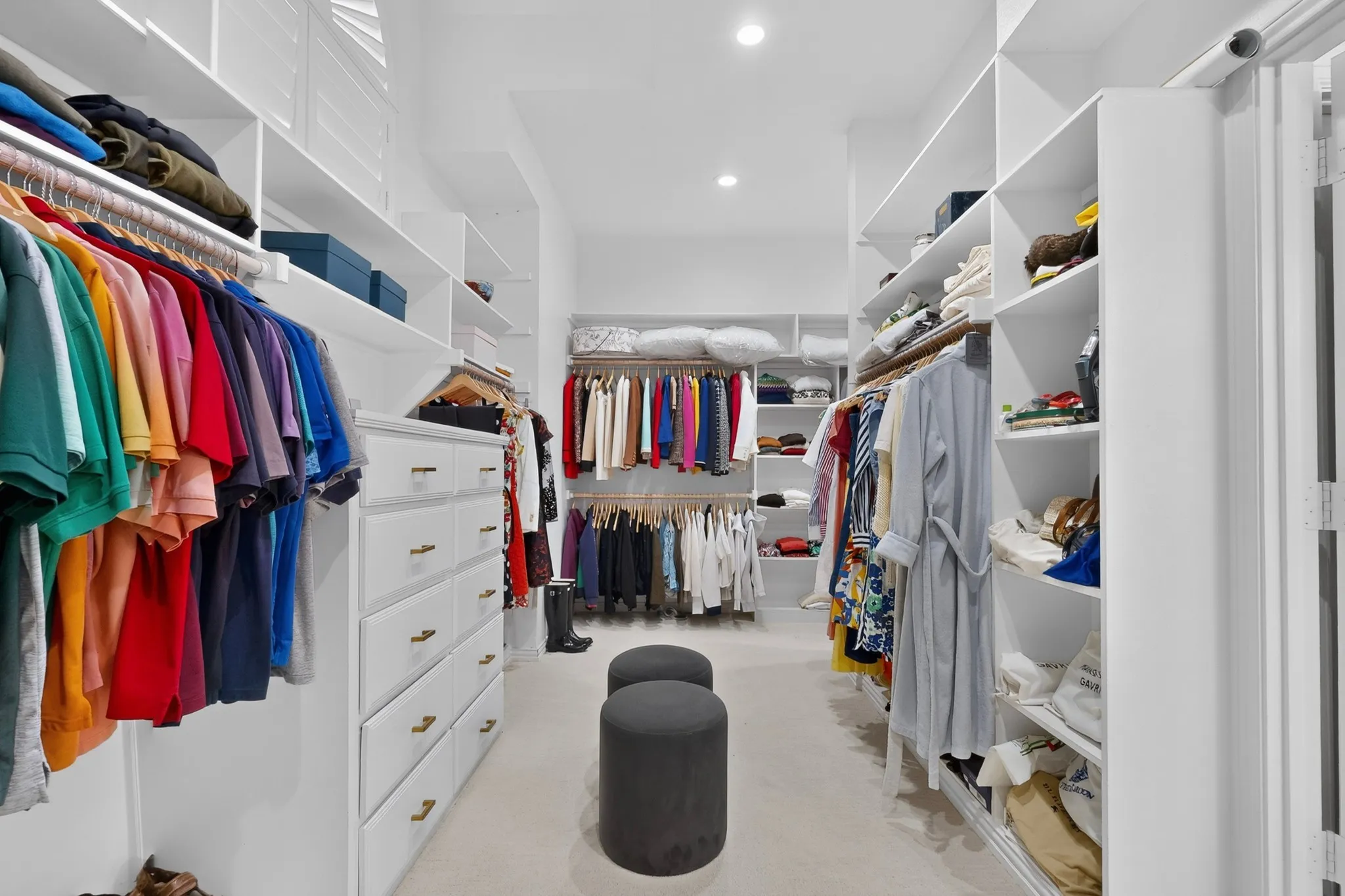 Custom built-in storage, extensive shelving, integrated hanging rods, recessed lighting, and wall-to-wall carpeting