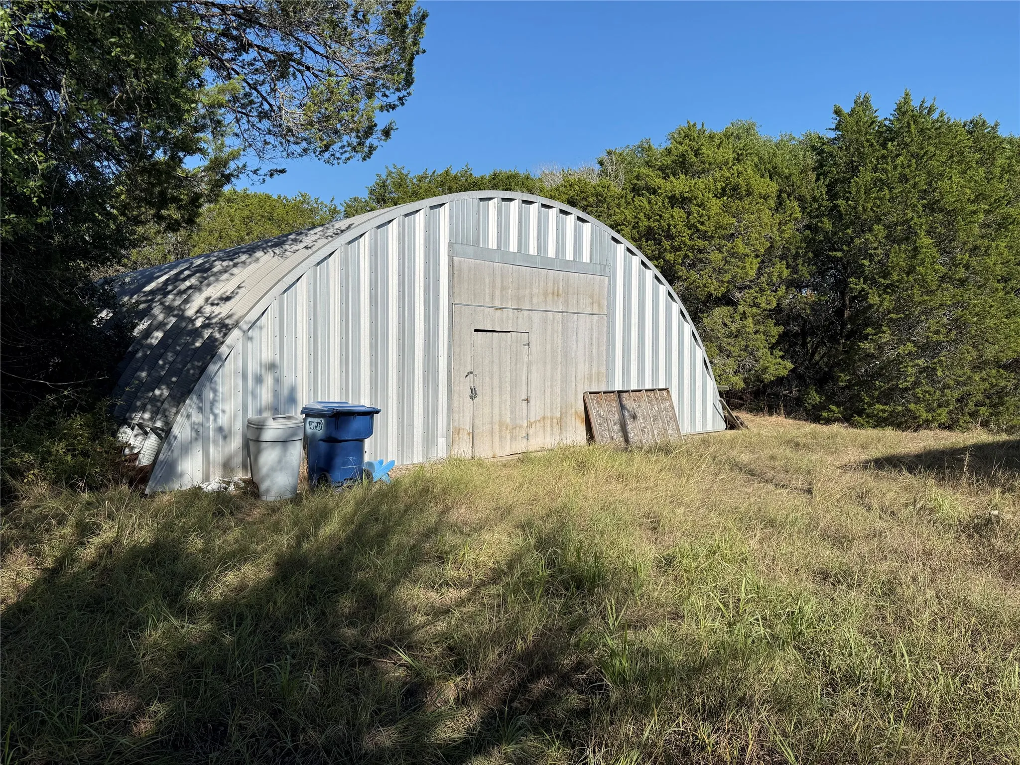 Quonset-style metal storage building featuring corrugated steel exterior walls and a double-door entry