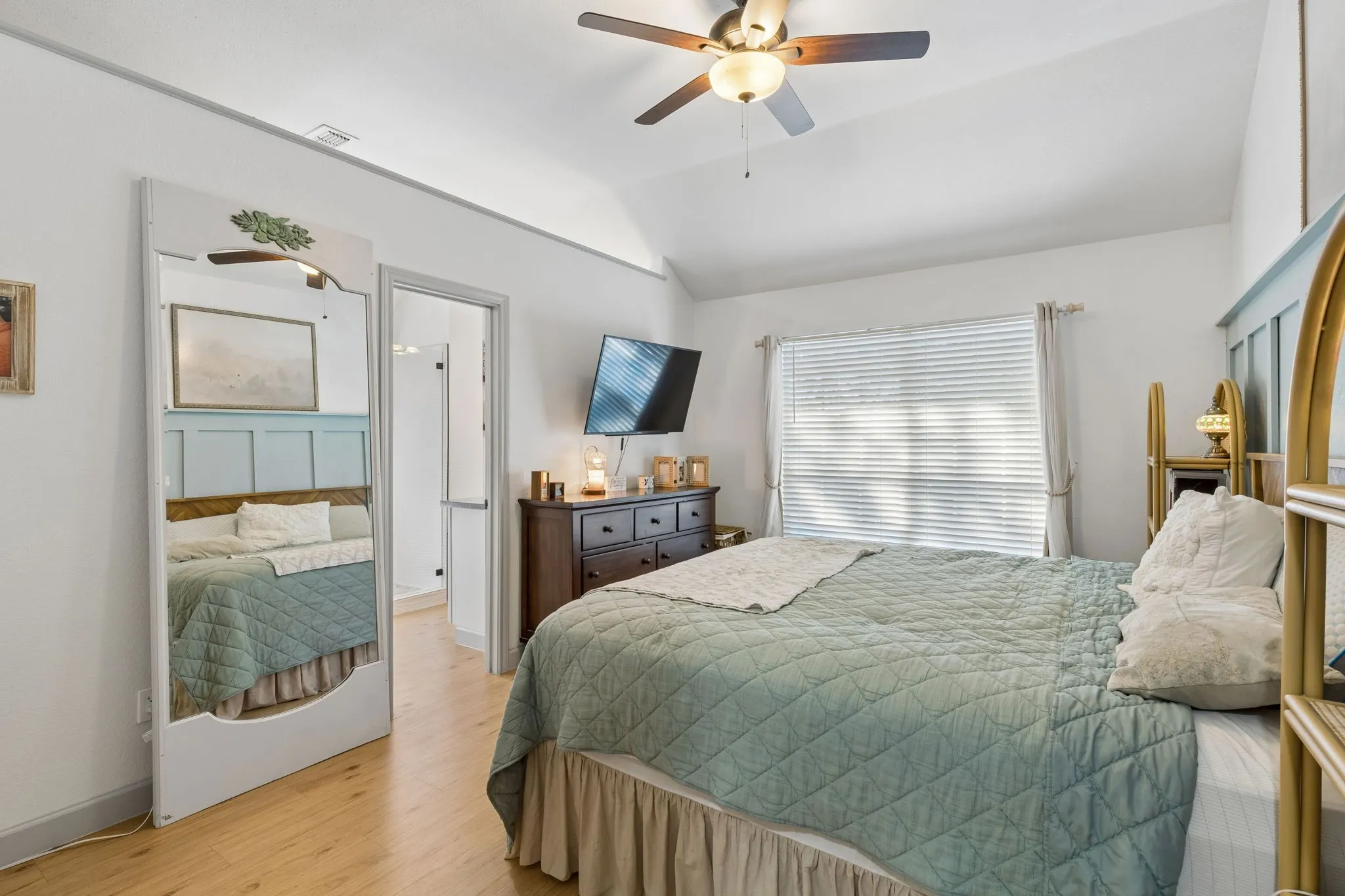 Welcome to the primary bedroom! When you enter you will see a large window, LVP flooring, a ceiling fan, and the entrance to the ensuite bath.
