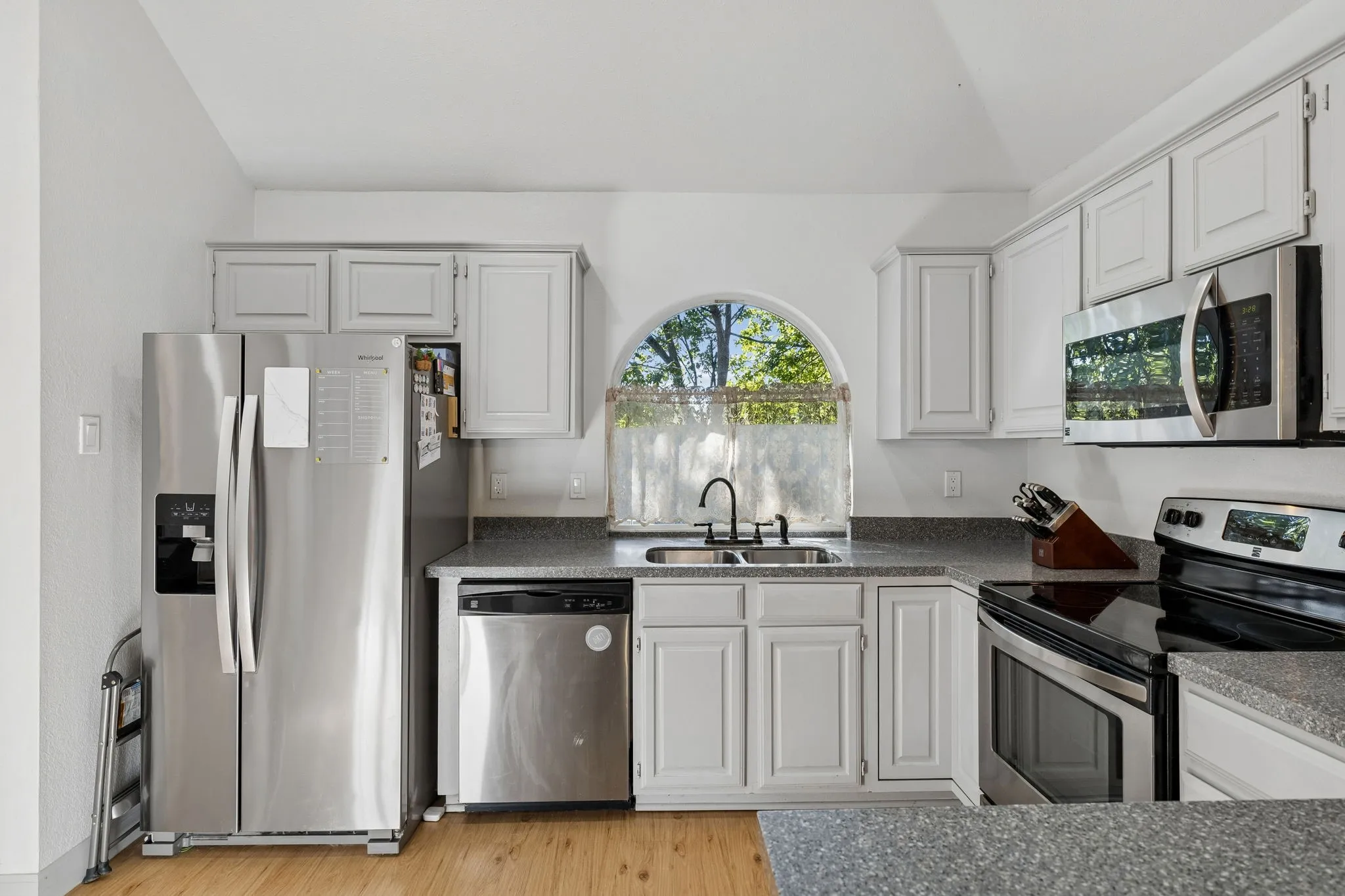 The lovely kitchen displays stainless steel appliances, recessed lighting, LVP flooring, vaulted ceilings, and smooth stone countertops.