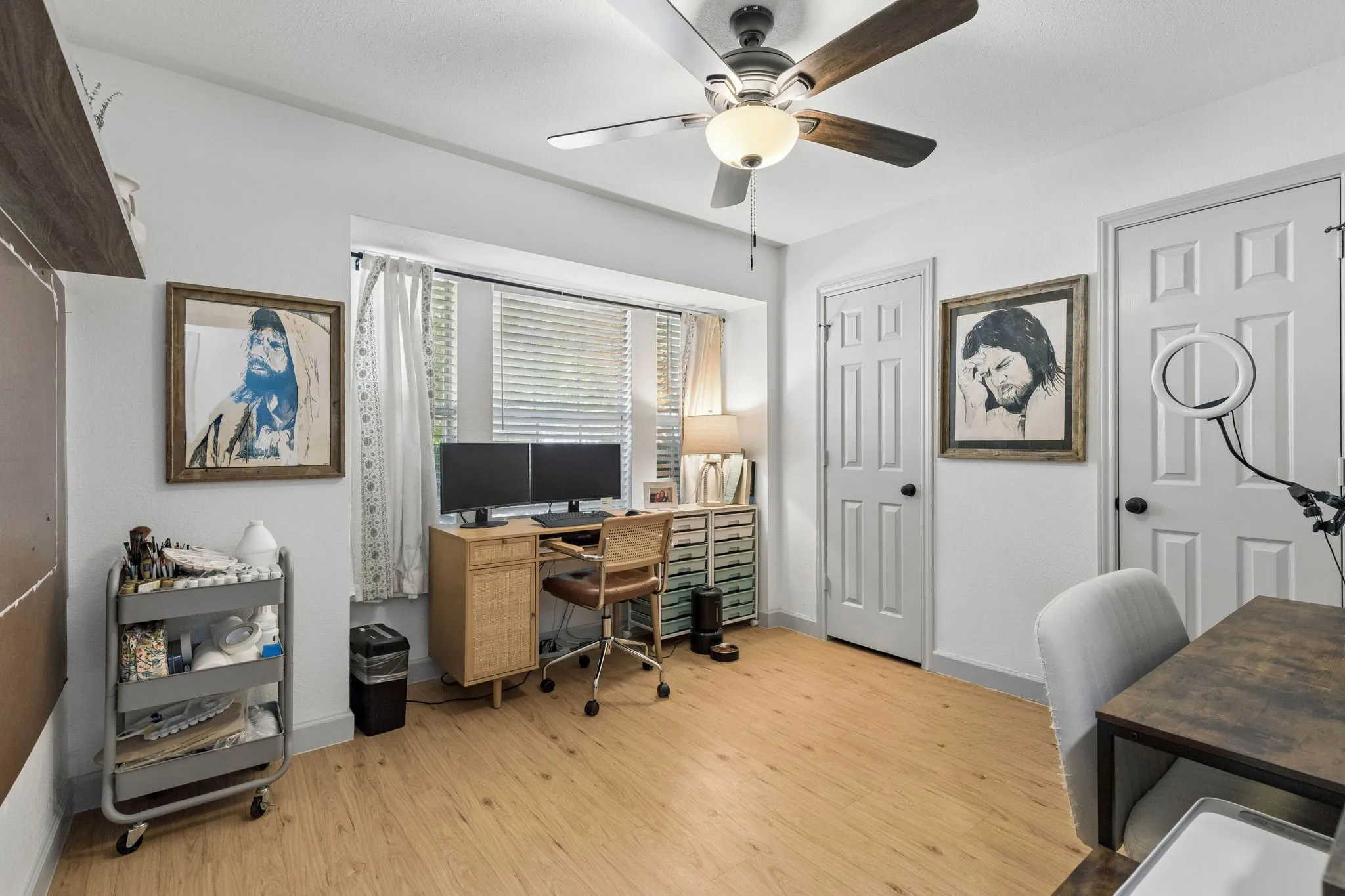 Another secondary bedroom being used as an office. This bedroom displays LVP flooring, a ceiling fan, large window and full wall length closet