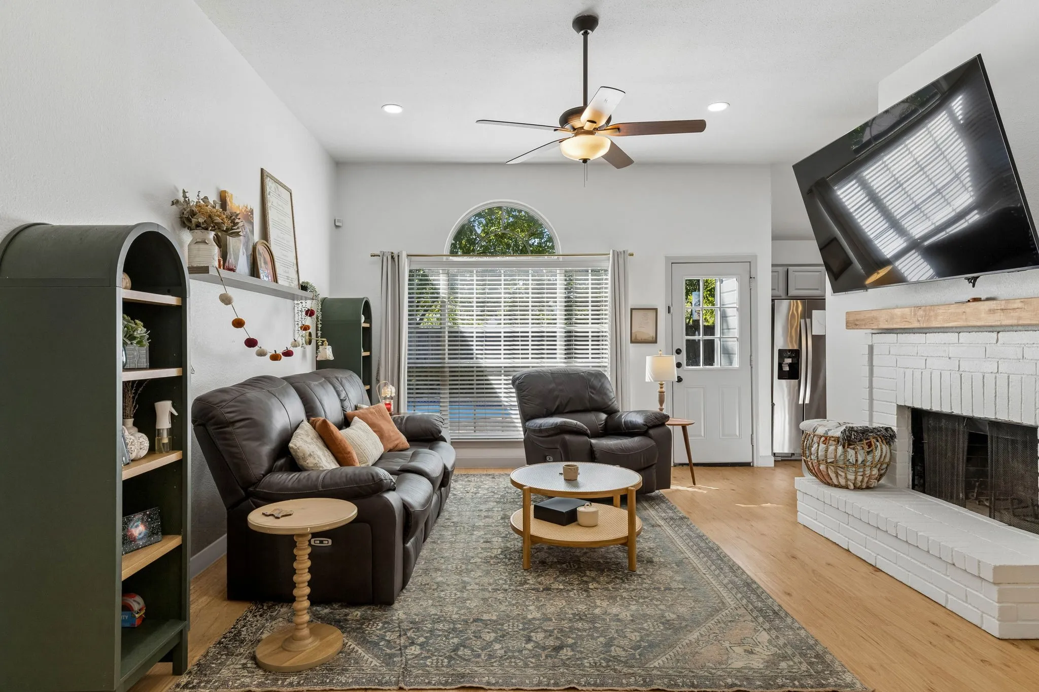 The spacious living room features a painted white brick wood burning fireplace, ceiling fan, LVP flooring, recessed lighting and views of the backyard.