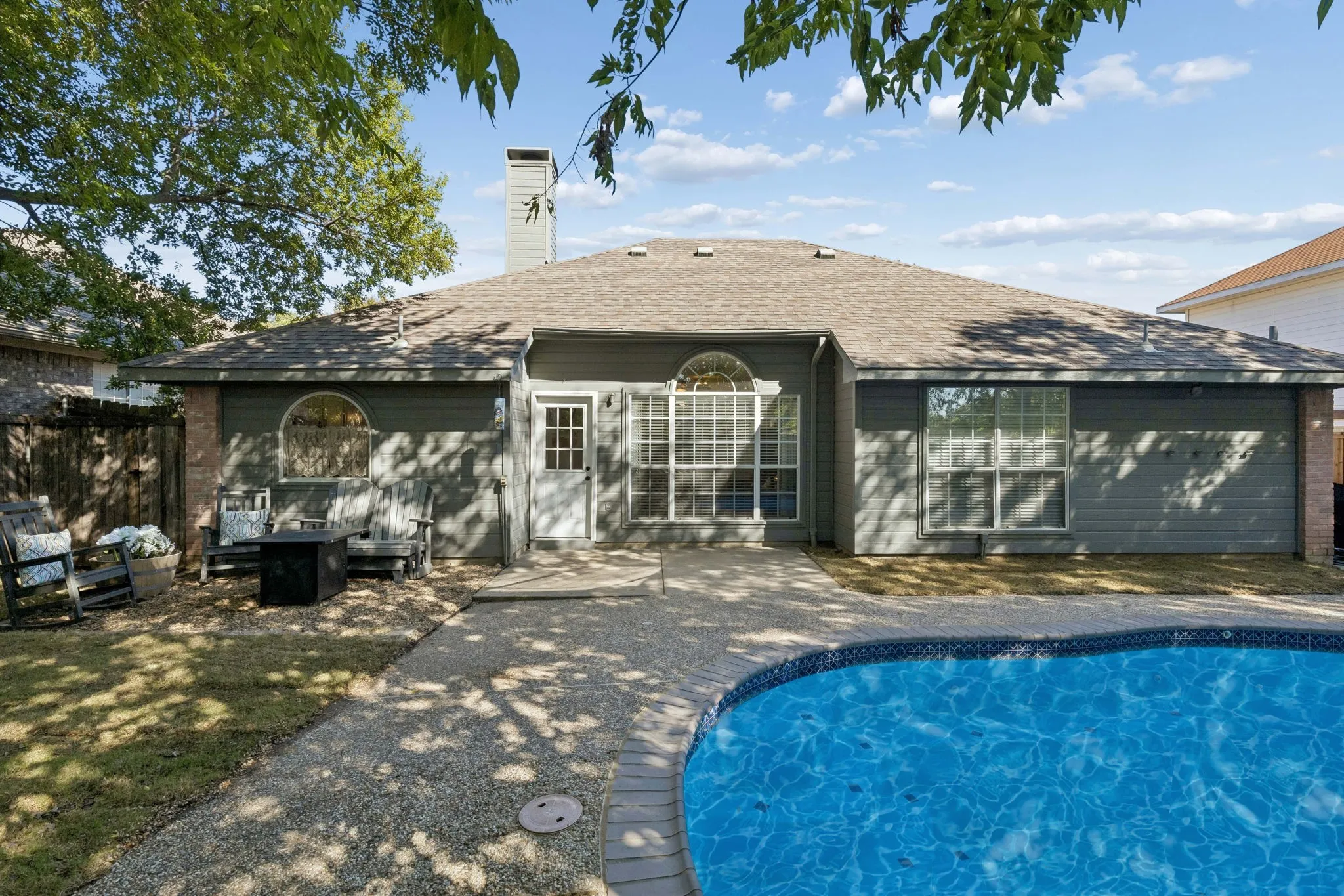 Another view of the yard displaying the patio, gravel sitting area and grassy lawn to the left.