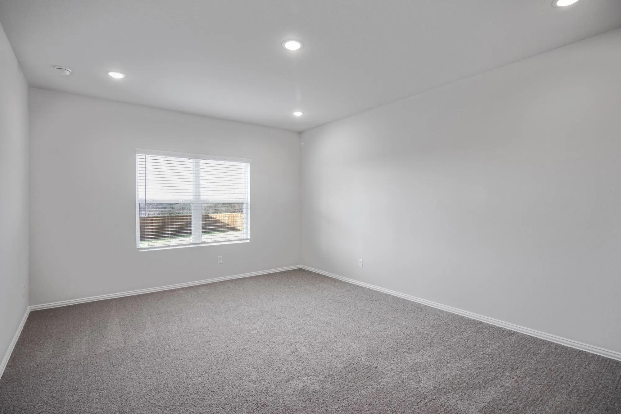 Recessed lighting illuminates neutral walls and gray carpeting