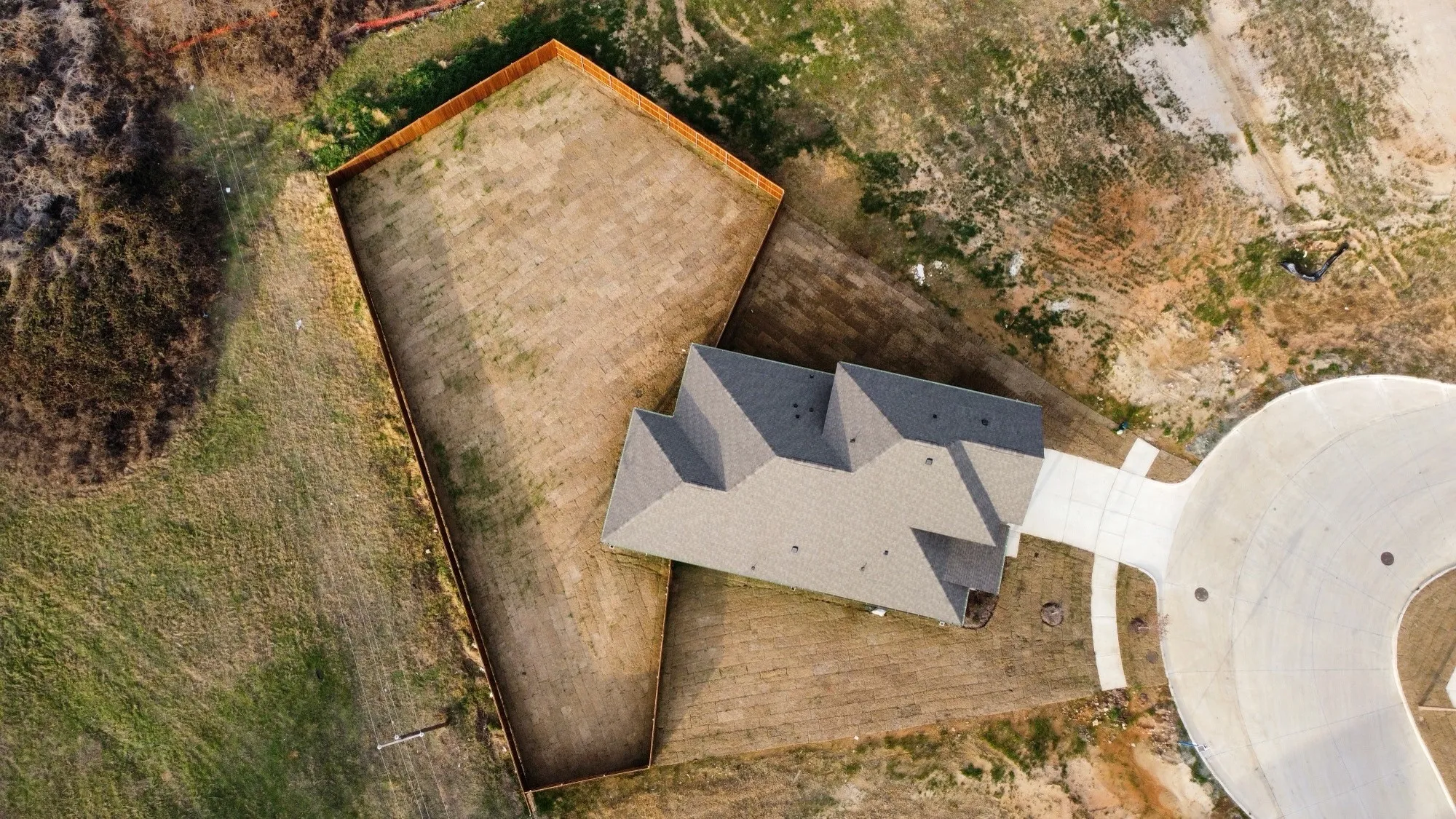 New construction residence featuring a multi-pitched roof, concrete driveway, and a partially fenced yard