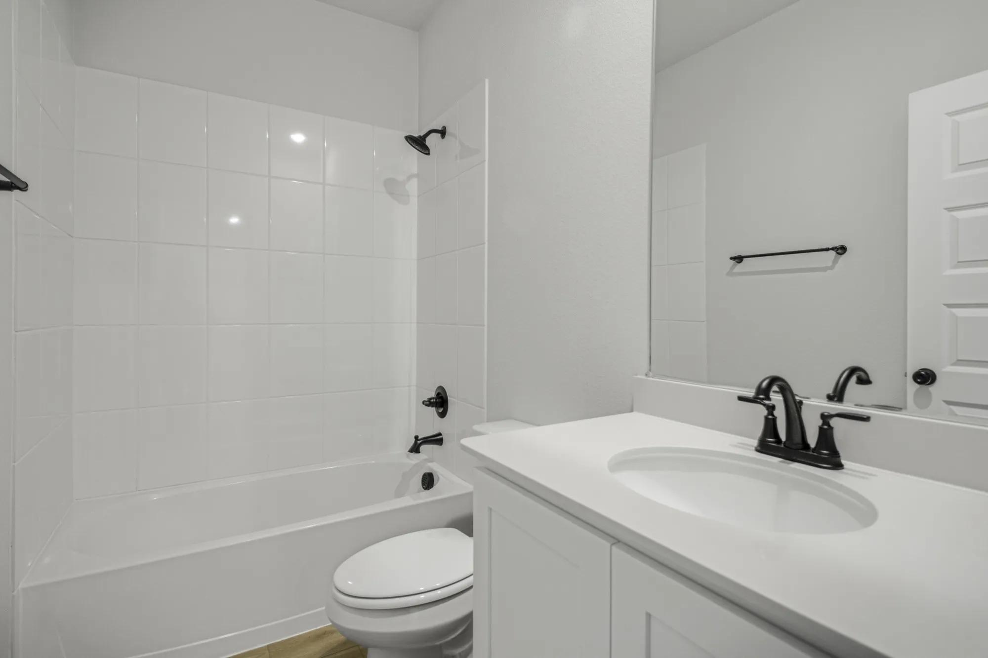 White tile tub and shower combination with matte black fixtures