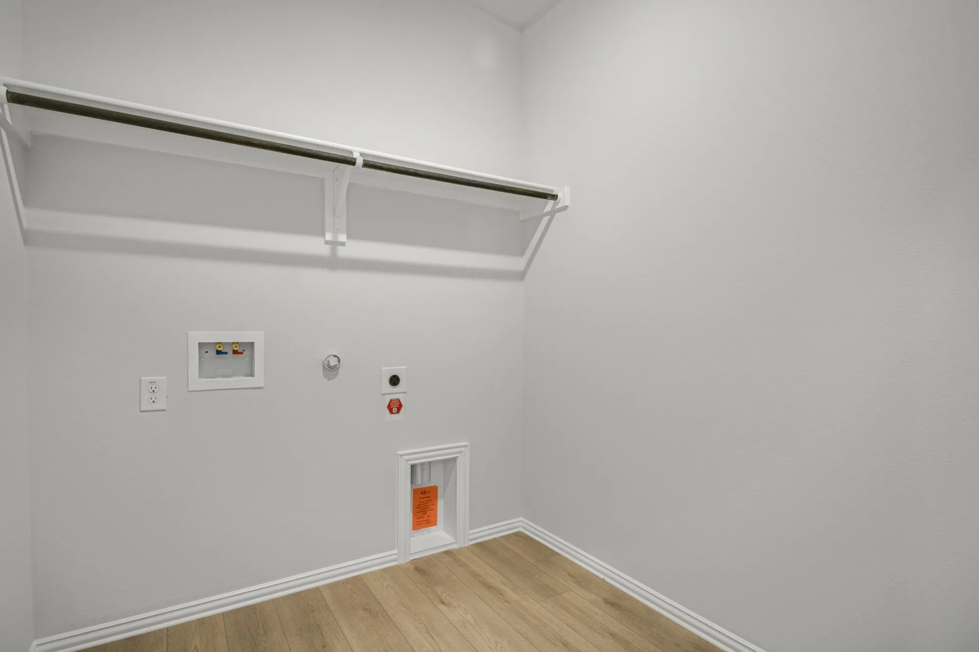 Laundry area with wood-finish flooring, white walls, and built-in shelving