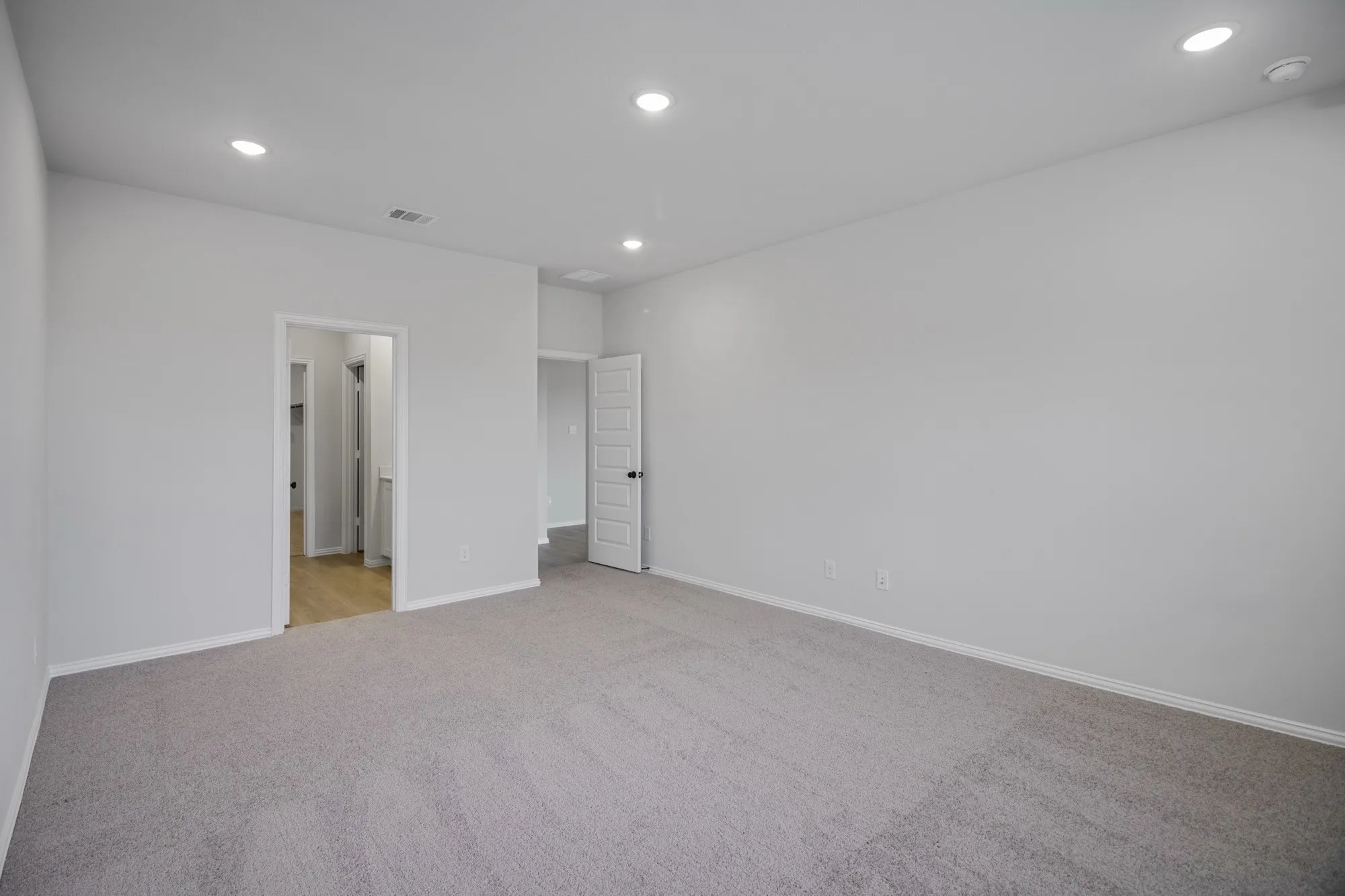 Recessed ceiling lighting, light gray wall paint, light gray carpet flooring, white trim, and white paneled doors