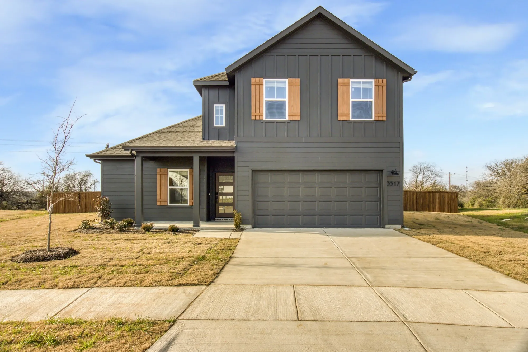 Two-story facade with board and batten and horizontal siding accents, covered entry, and wood-finish window shutters