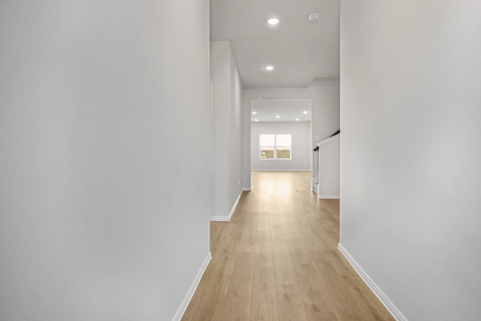 Hallway with recessed lighting, light wood-finish flooring, white walls, and white trim