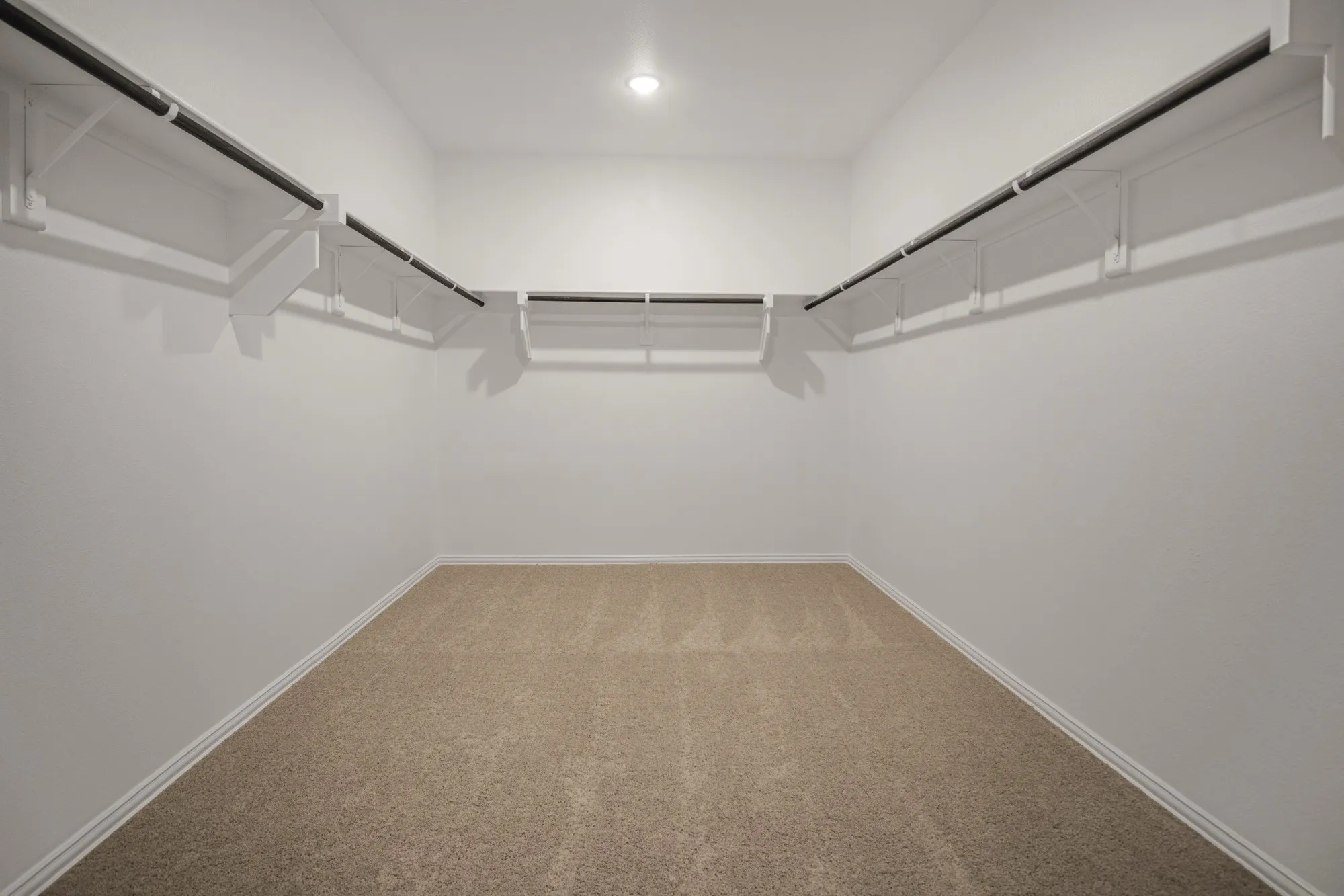 Expansive walk-in closet featuring built-in shelving, hanging rods, and recessed lighting