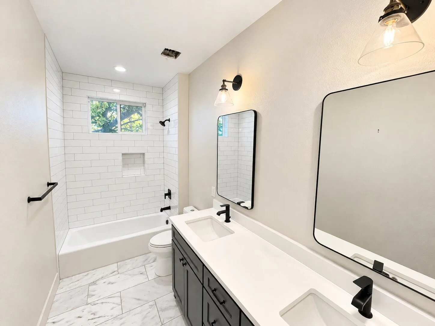 Dual vanity with white solid surface countertop, undermount sinks, and matte black fixtures