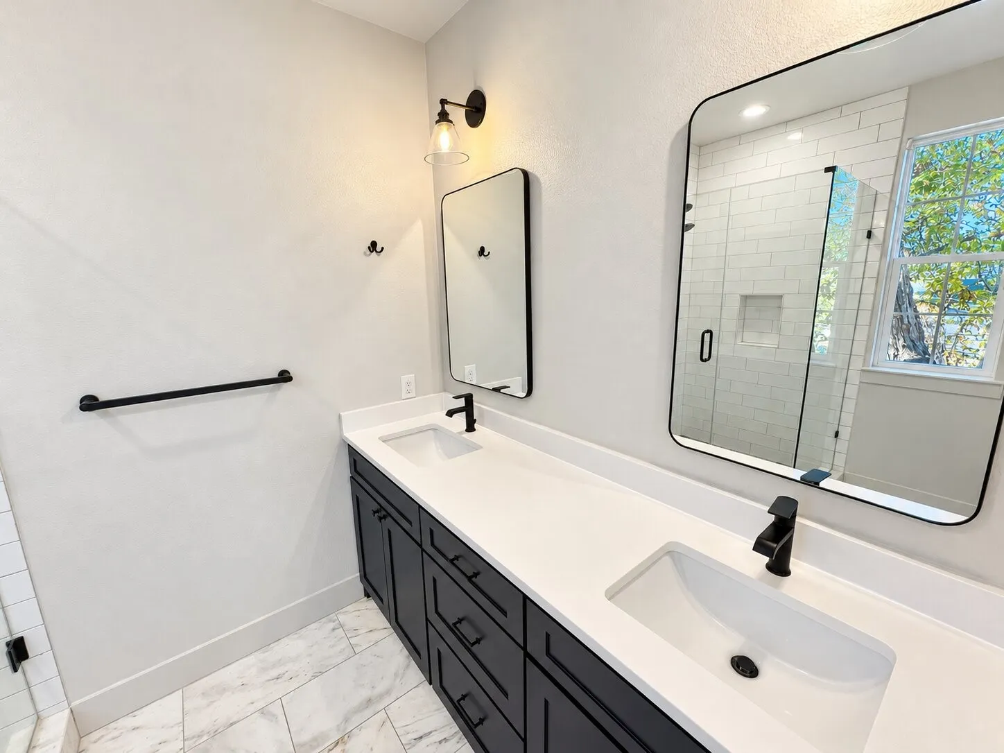 Modern primary bathroom featuring a dual-sink vanity with white quartz countertop, matte black hardware and faucets, and an undermount basin design