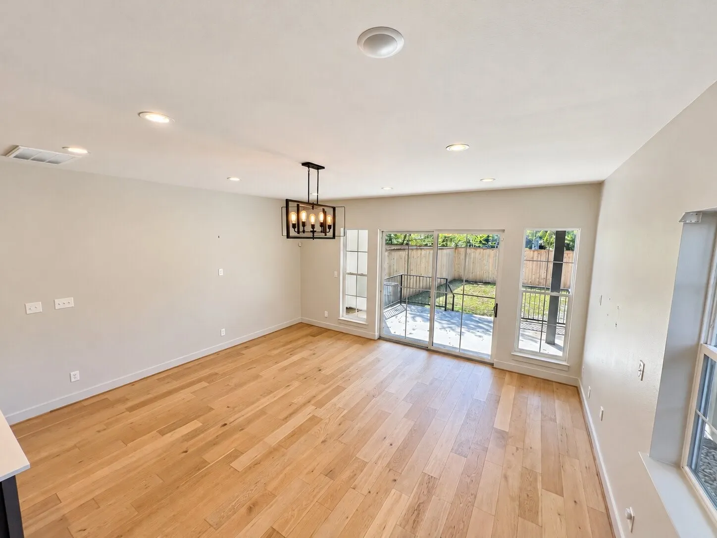 Hardwood flooring, recessed lighting, modern chandelier, sliding glass doors, and a private outdoor patio