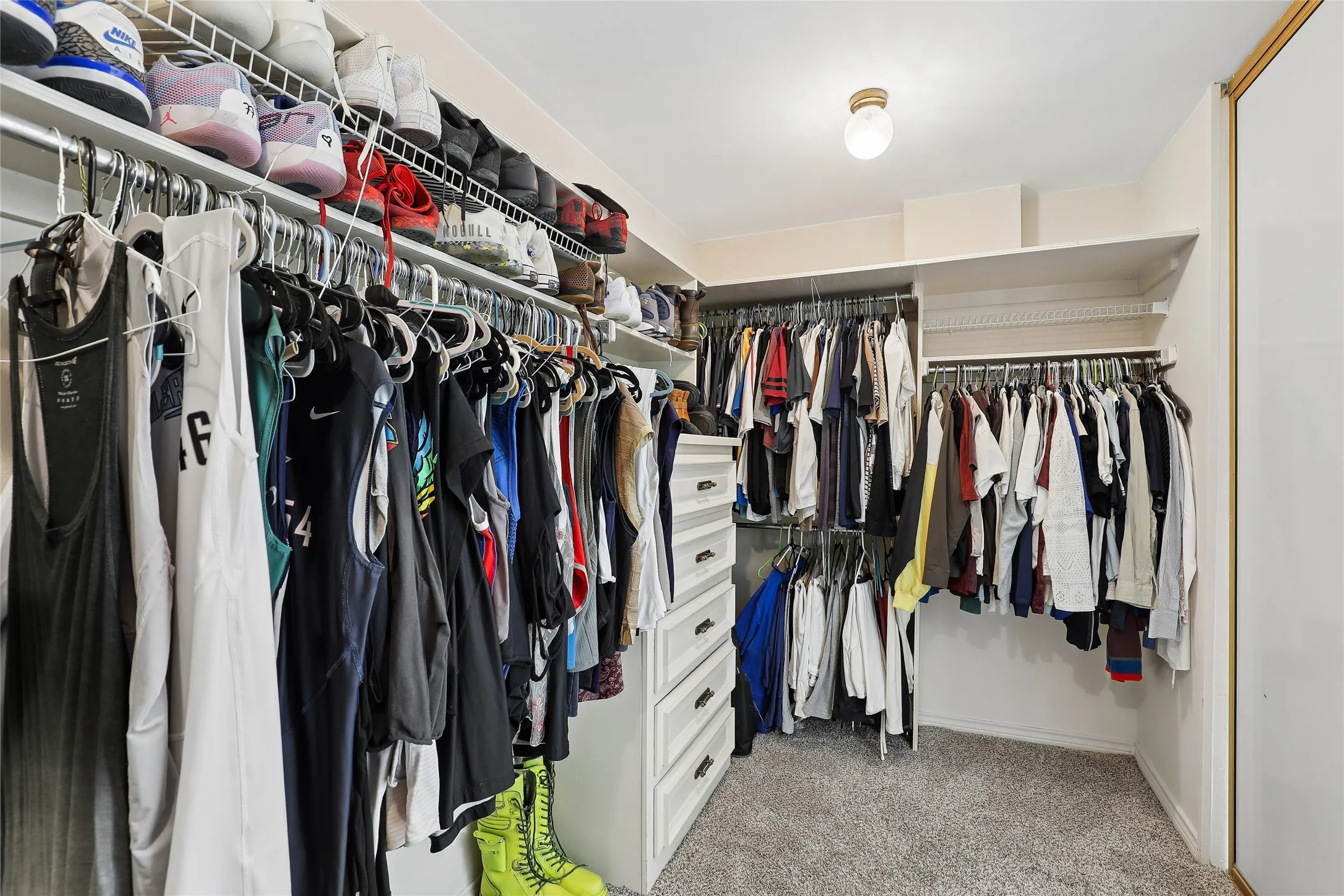 Luxury walk-in closet featuring built-in shelving, multiple hanging rods, integrated drawer storage, and carpet flooring
