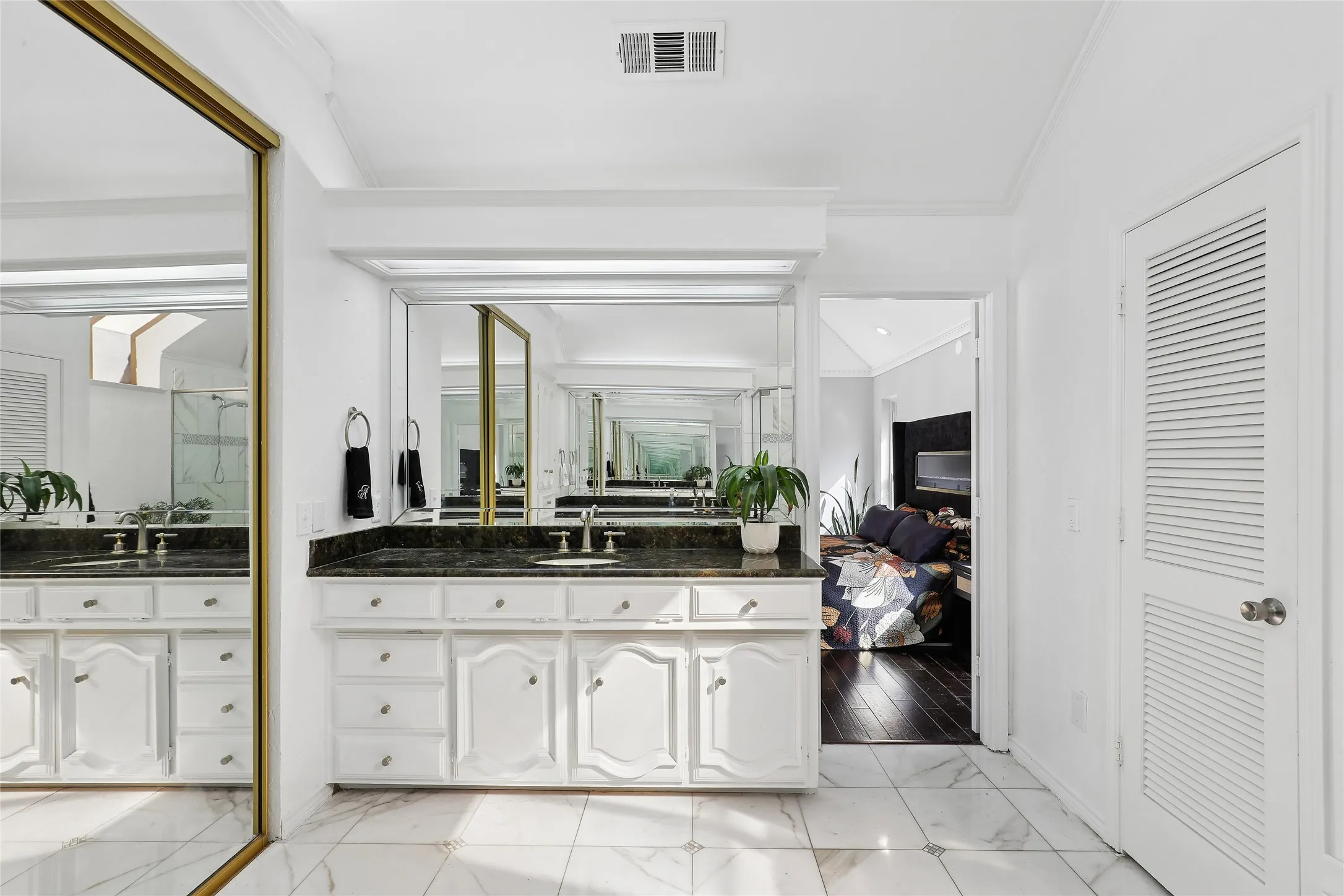 Dual vanity with dark stone countertop, white cabinetry, and wall-mounted mirrors