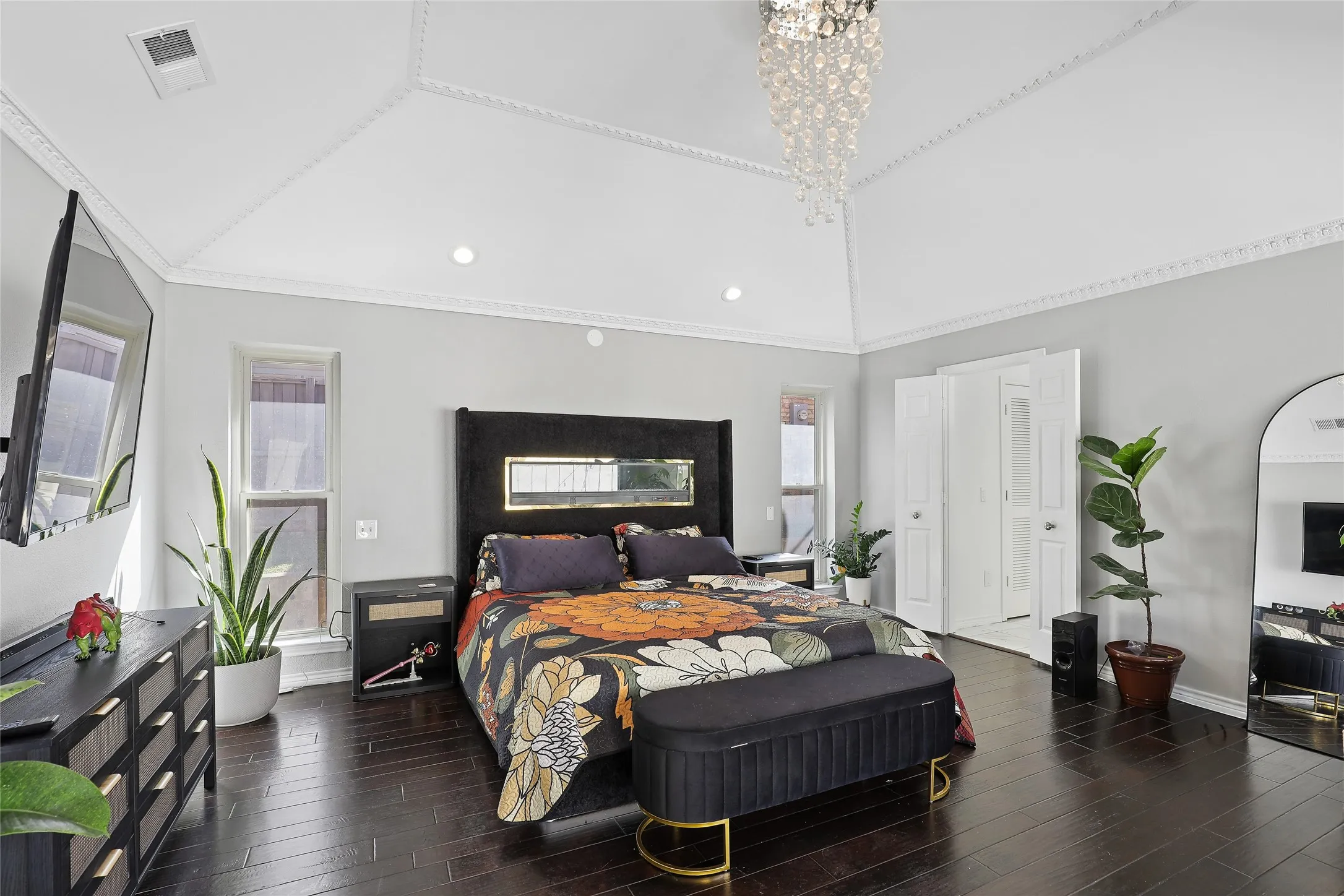 Vaulted ceiling with decorative molding, recessed lighting, dark wood-finish flooring, and a crystal chandelier.