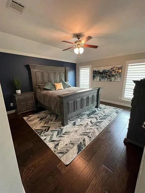 Wood-finish flooring, crown molding, ceiling fan with integrated lighting, and plantation shutters