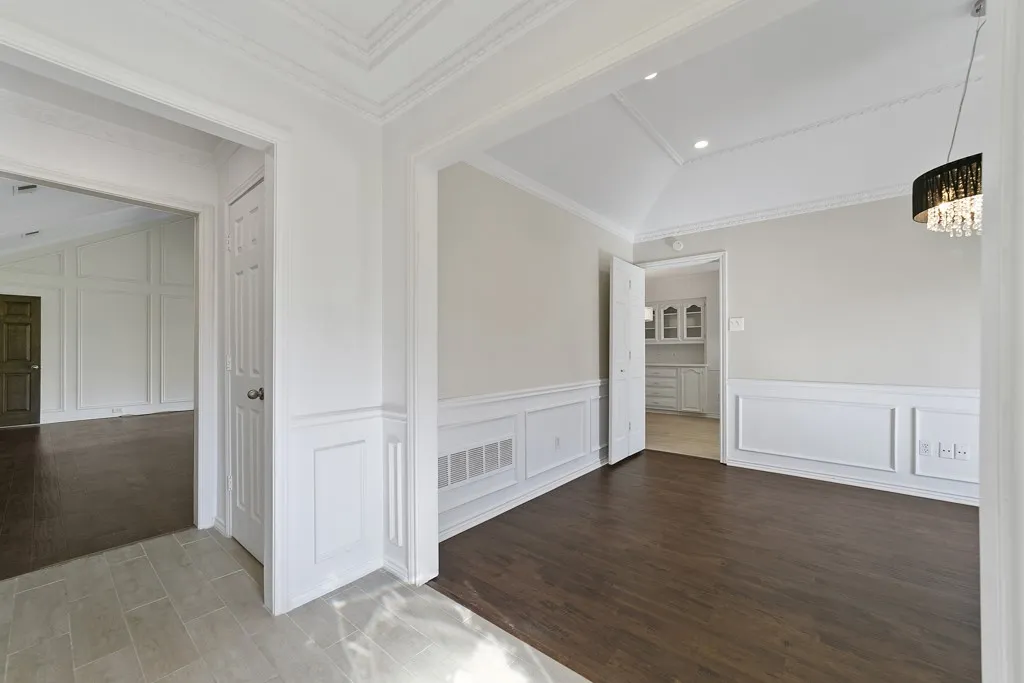 Vaulted ceiling with crown molding, wainscoting, wood-finish flooring, and a decorative light fixture