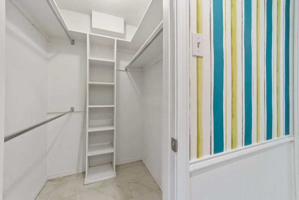 Walk-in closet featuring built-in shelving, dual hanging rods, and tile flooring
