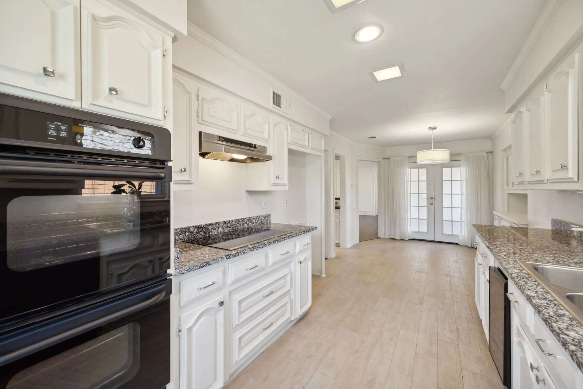 Kitchen featuring white cabinetry, stone countertops, a built-in oven, and wood-finish flooring