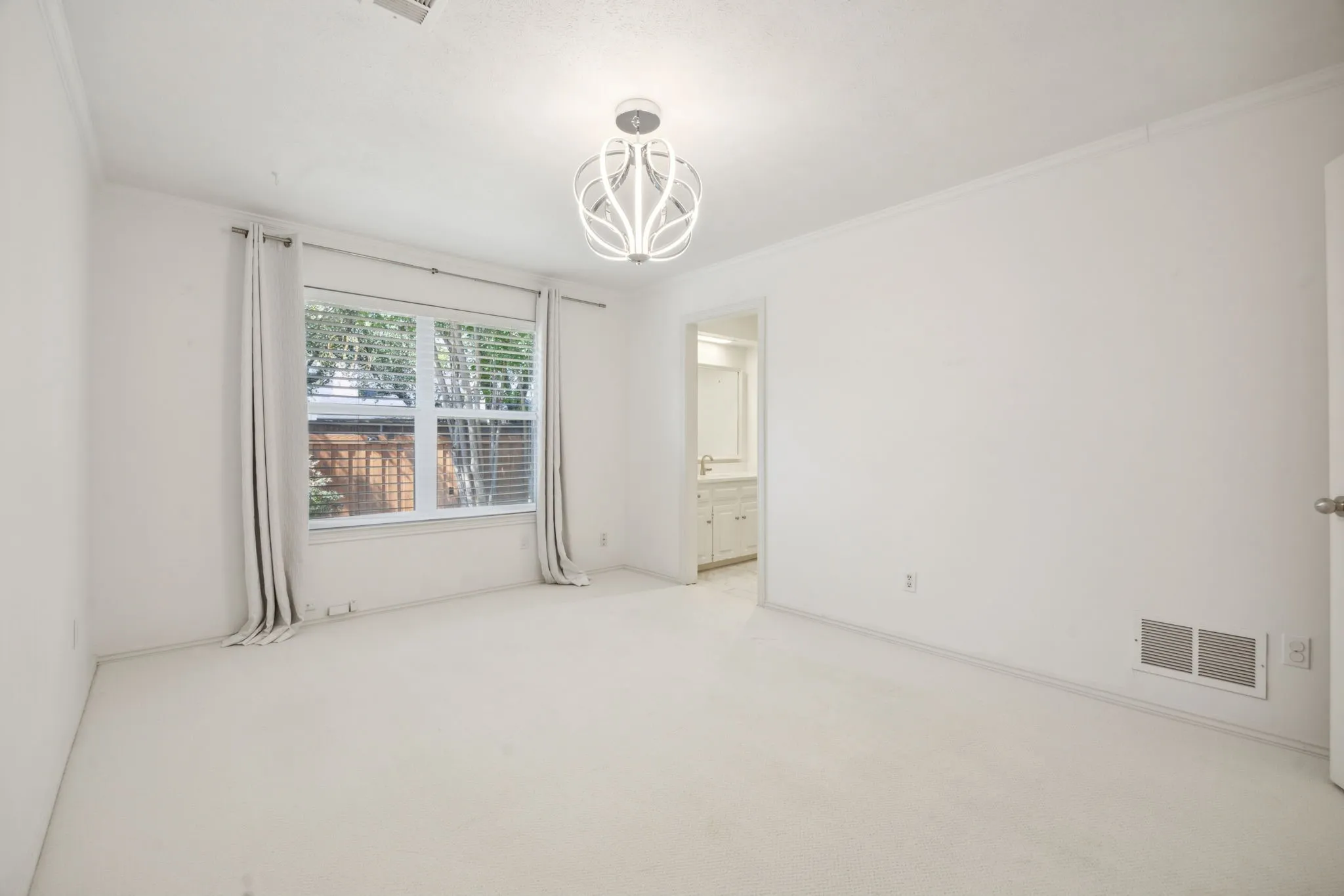 Recessed window with blinds, overhead decorative light fixture, and light-colored carpeting