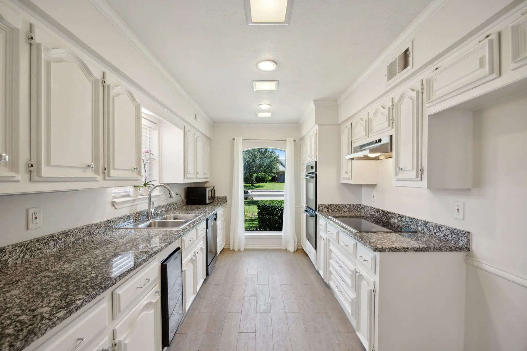 Kitchen with white cabinetry, granite countertops, wood-finish flooring, recessed lighting, and a built-in oven