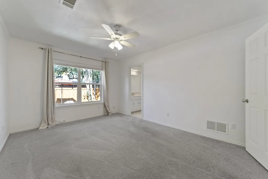 Carpeted room with a ceiling fan, a window, and white walls