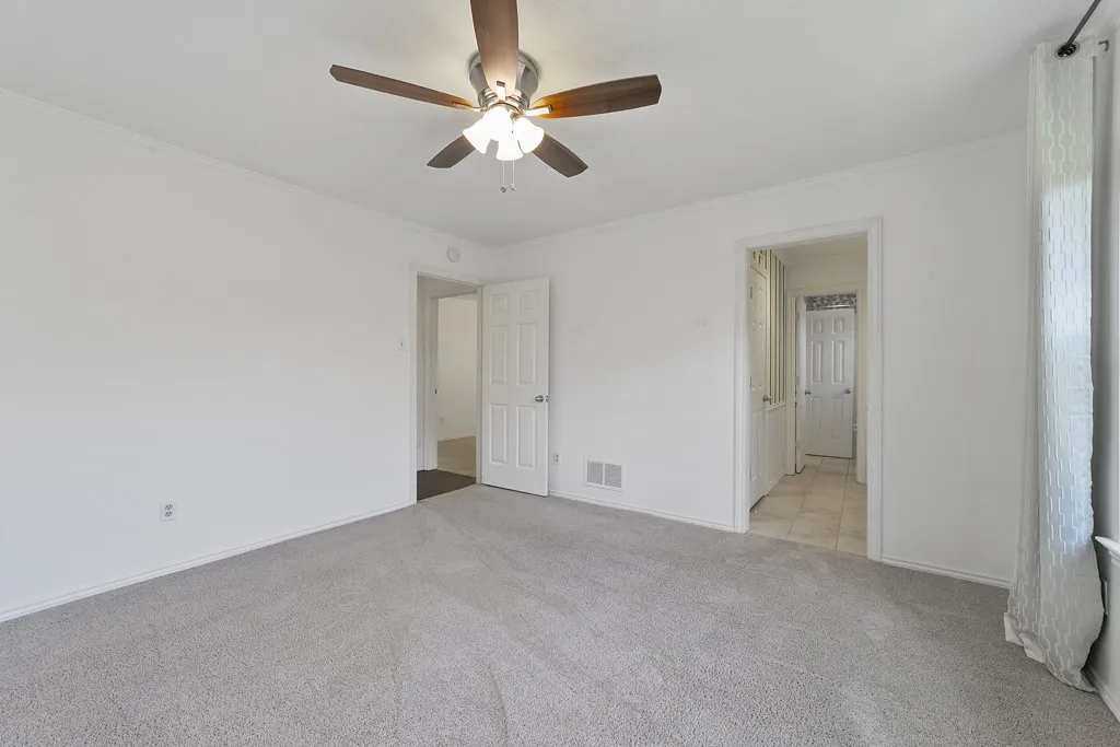 Light gray carpet flooring, white walls, ceiling fan with integrated lighting, white trim, and a white paneled door