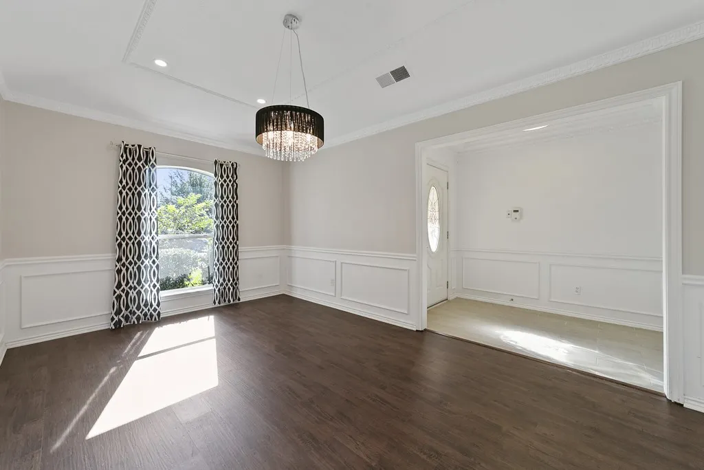 Dark wood-finish flooring with white wainscoting and crown molding