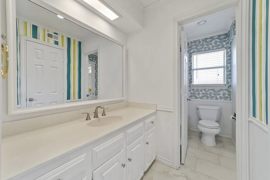 Elongated vanity with integrated sink, brushed nickel faucet, and paneled cabinetry