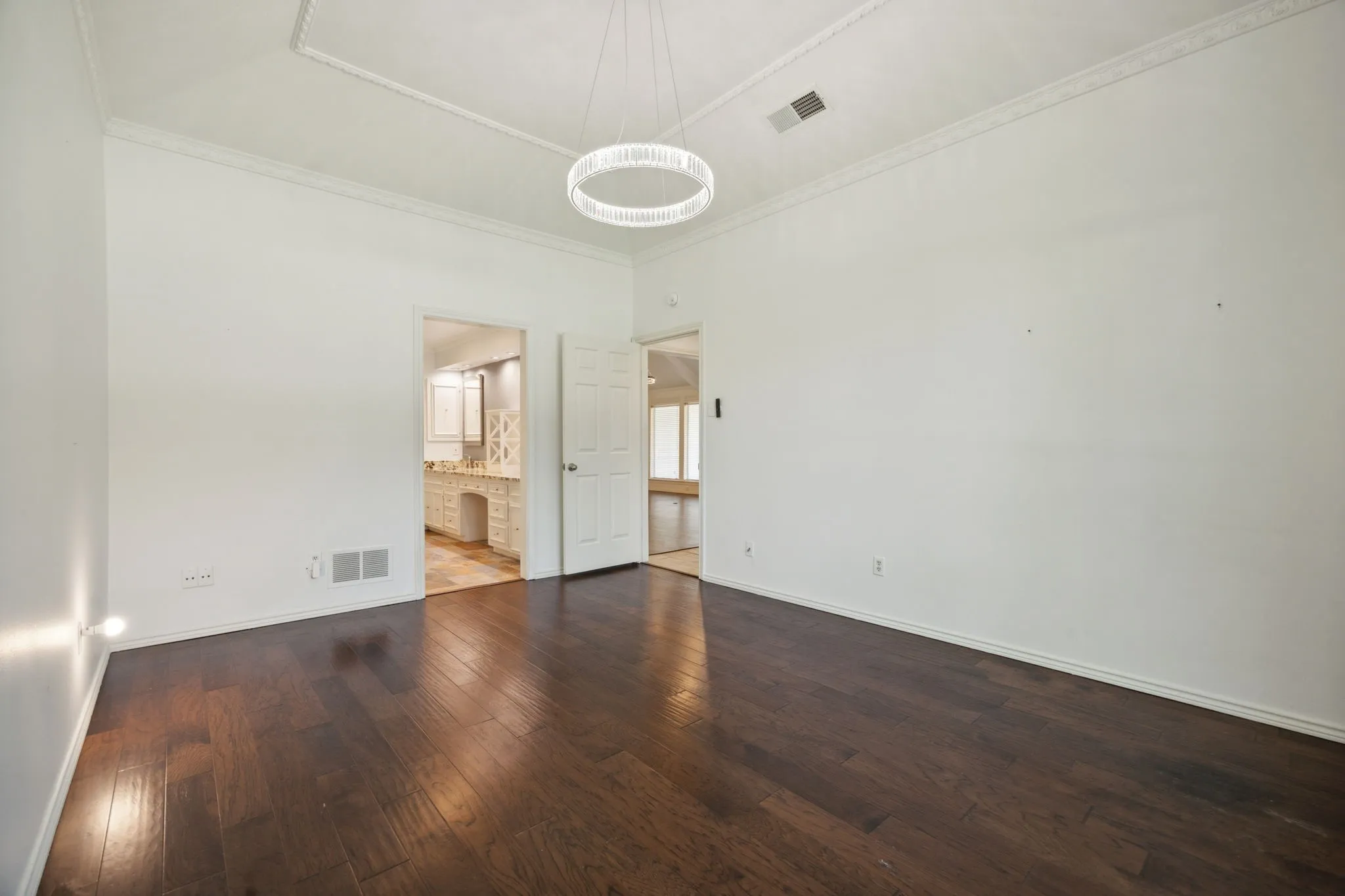 Rich wood-finish flooring, crisp white walls, and a recessed ceiling with crown molding