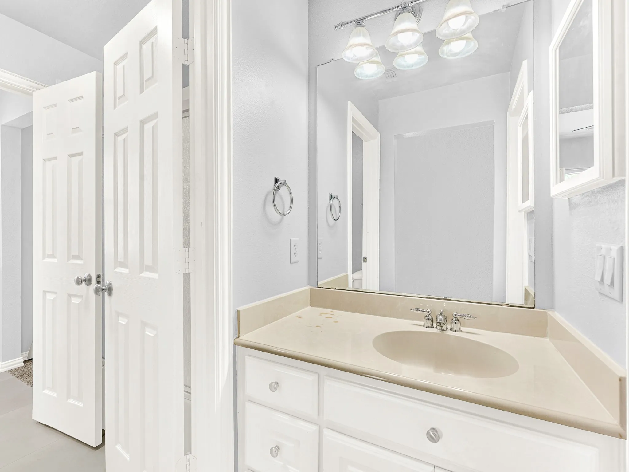 Built-in vanity with an integrated sink, polished chrome faucet, and expansive wall mirror
