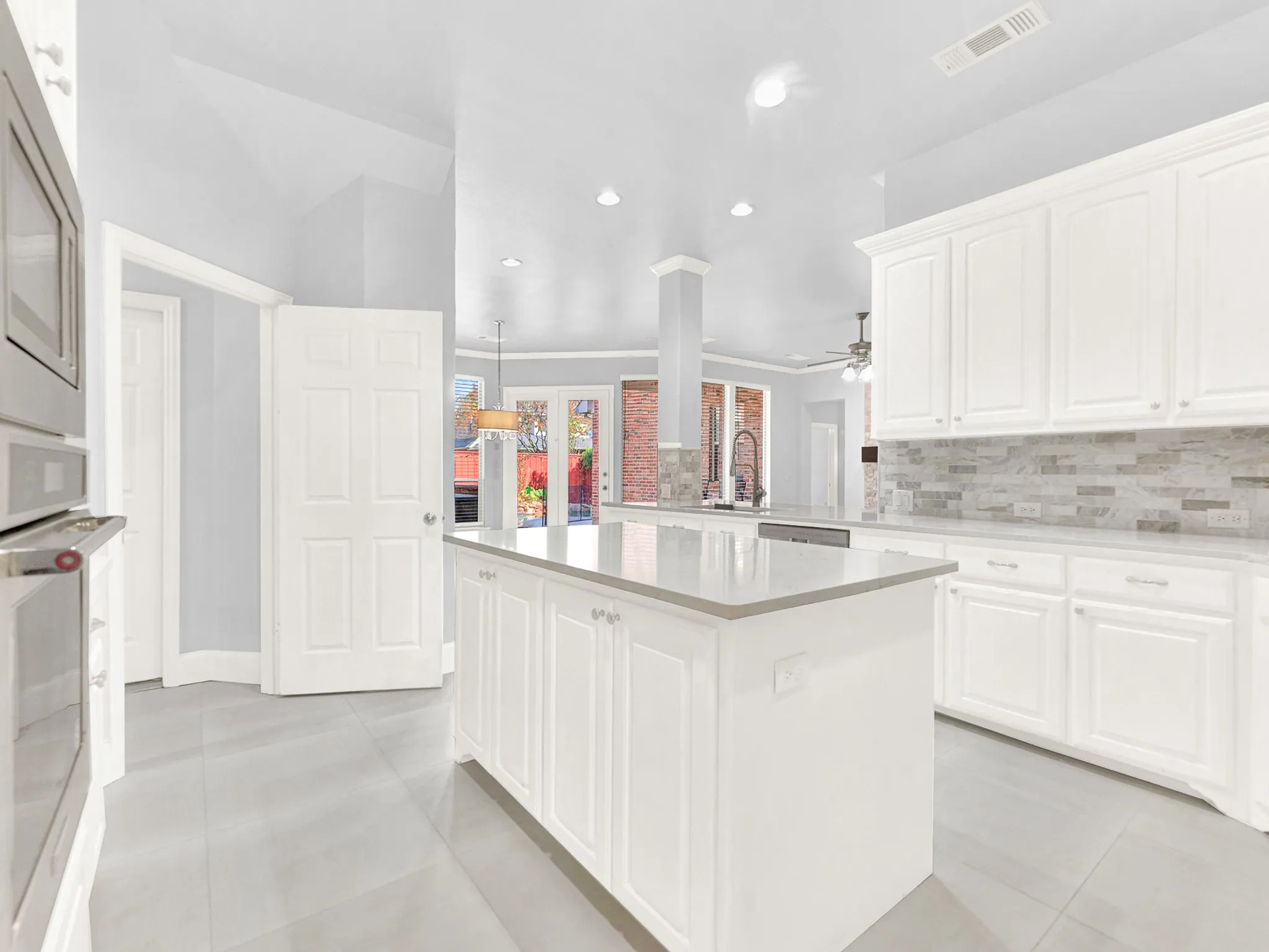 Kitchen featuring white cabinetry, light gray countertops, a tile backsplash, stainless steel appliances, and large format floor tiling