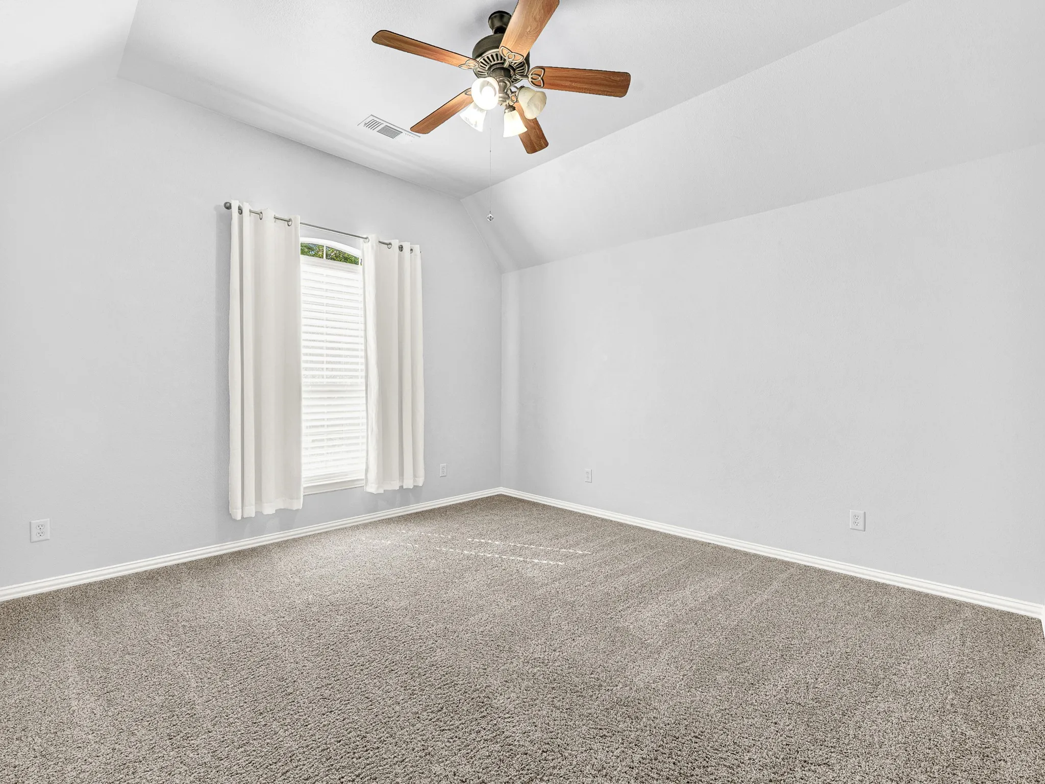 Carpeted flooring, vaulted ceiling, window with blinds, ceiling fan with light fixture