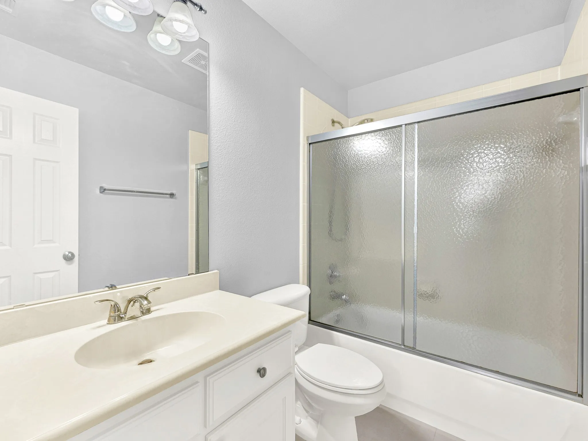 White vanity with integrated sink, brushed nickel faucet, large wall-mounted mirror, and overhead vanity lighting