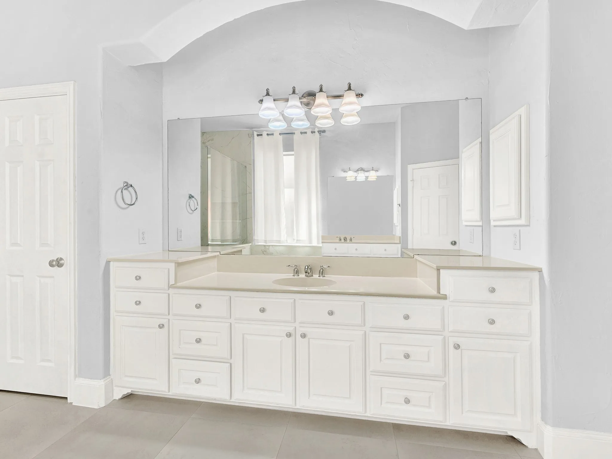 Expansive vanity featuring a single basin sink, white cabinetry, and light-toned countertop