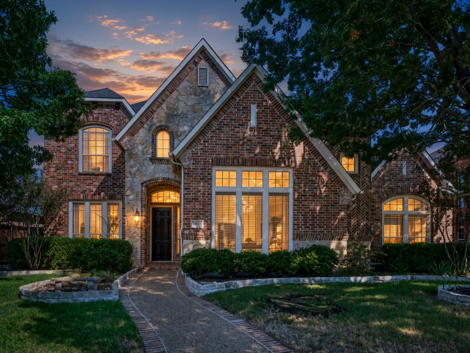 Brick and stone exterior with multiple gables, arched entry, and a paver walkway