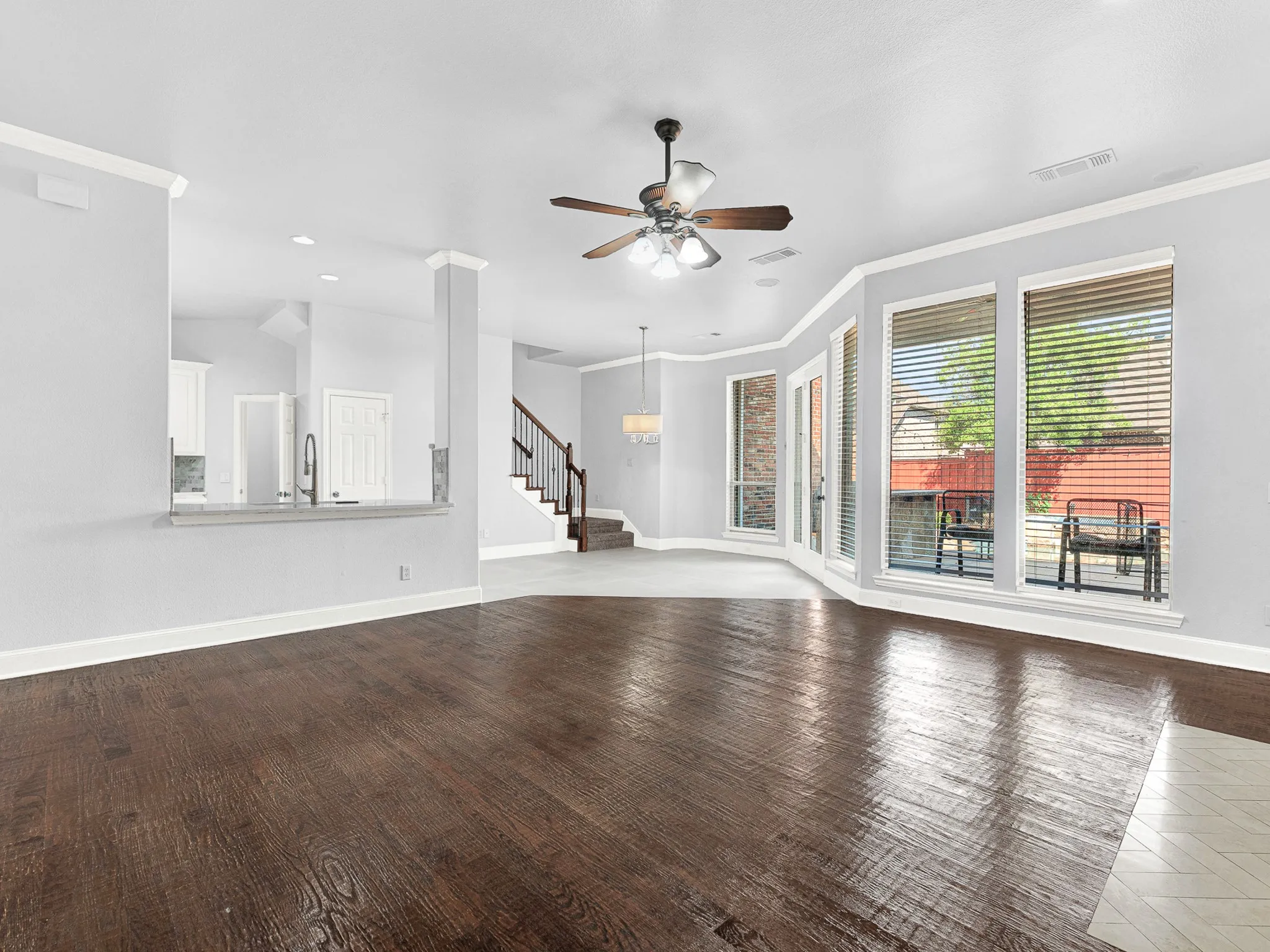 Wood-finish flooring, bay window with multiple panes, ceiling fan light fixture, staircase with wood handrail, and a built-in half-wall with countertop