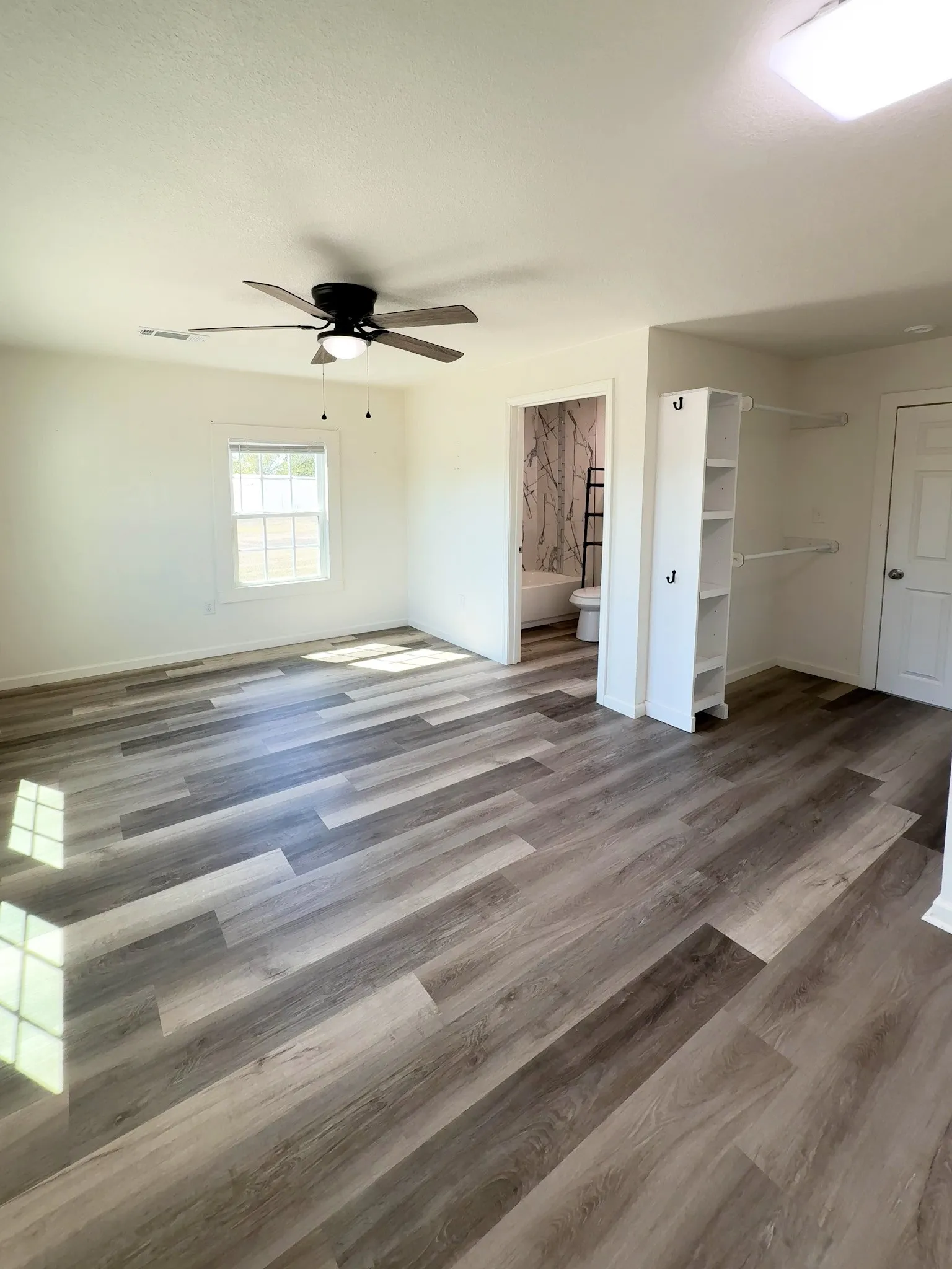 Primary bedroom with ceiling fan, natural light, and access to a private porch