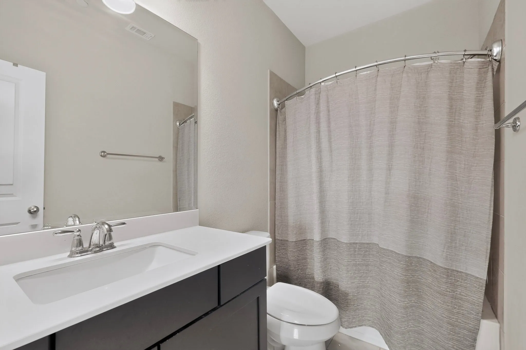 Bathroom featuring a rectangular undermount sink, dual-handle chrome faucet, dark wood-finish vanity, and a curved shower rod