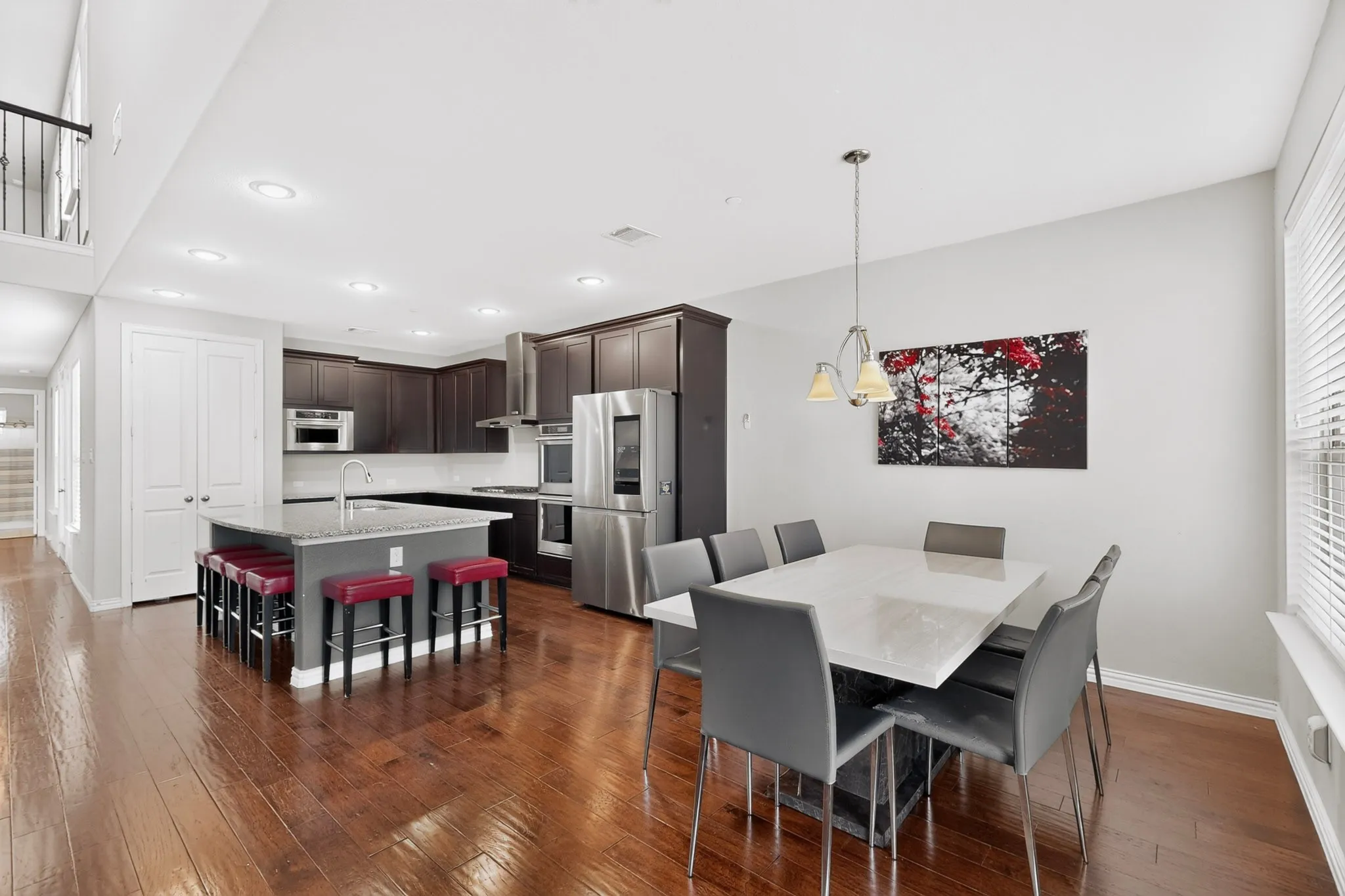 Hardwood flooring throughout, recessed lighting, and a kitchen island with built-in cabinetry and a sink