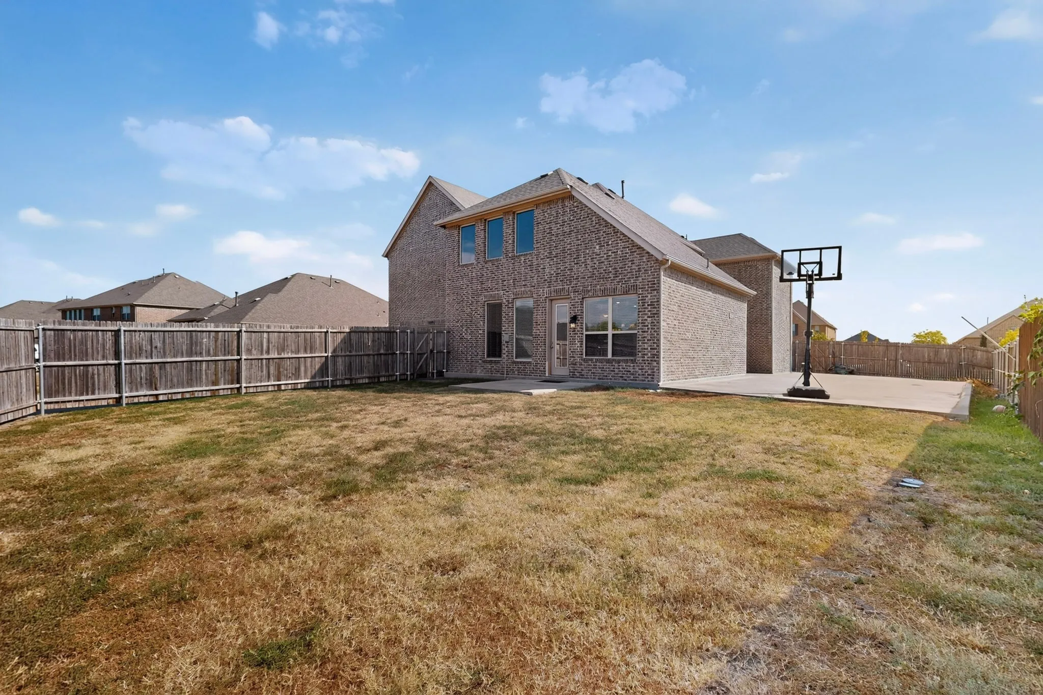 Brick exterior with multiple windows and a concrete patio