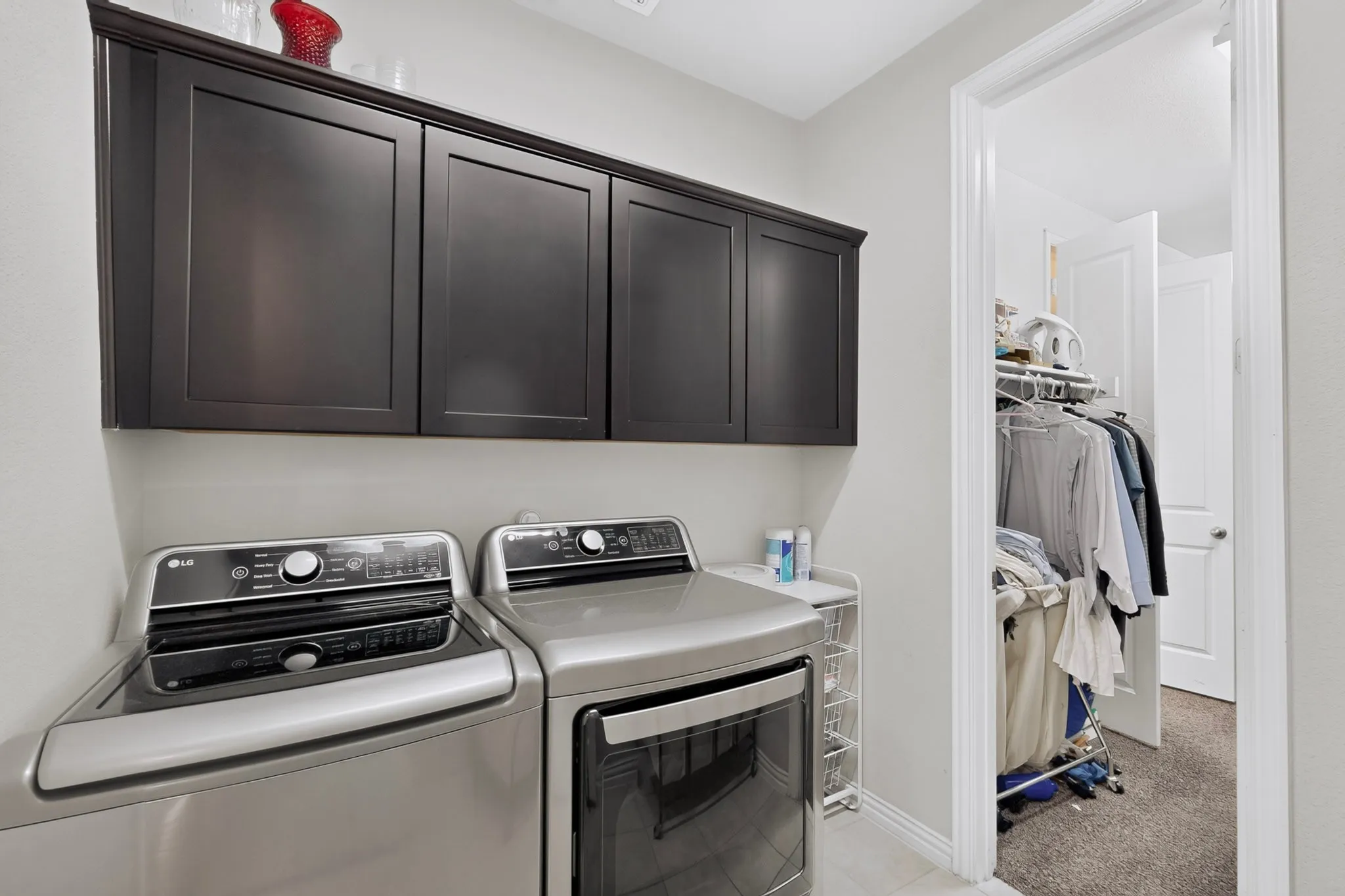 Built-in dark cabinetry providing storage, tiled flooring, and a large doorway opening to an additional storage area