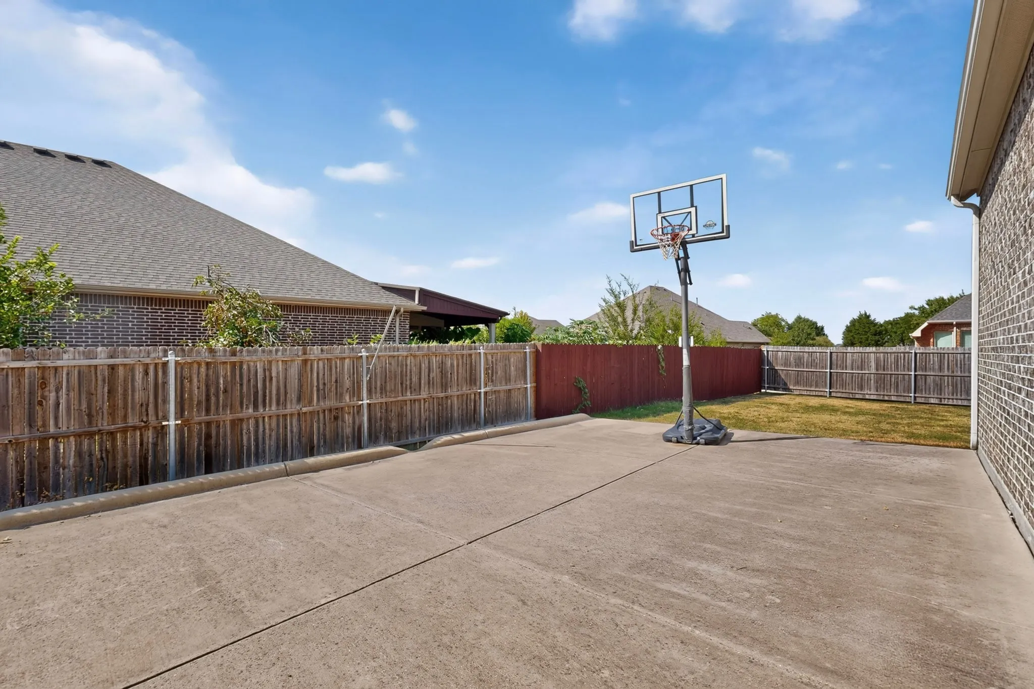 Paved concrete patio area with brick exterior wall and wood privacy fencing