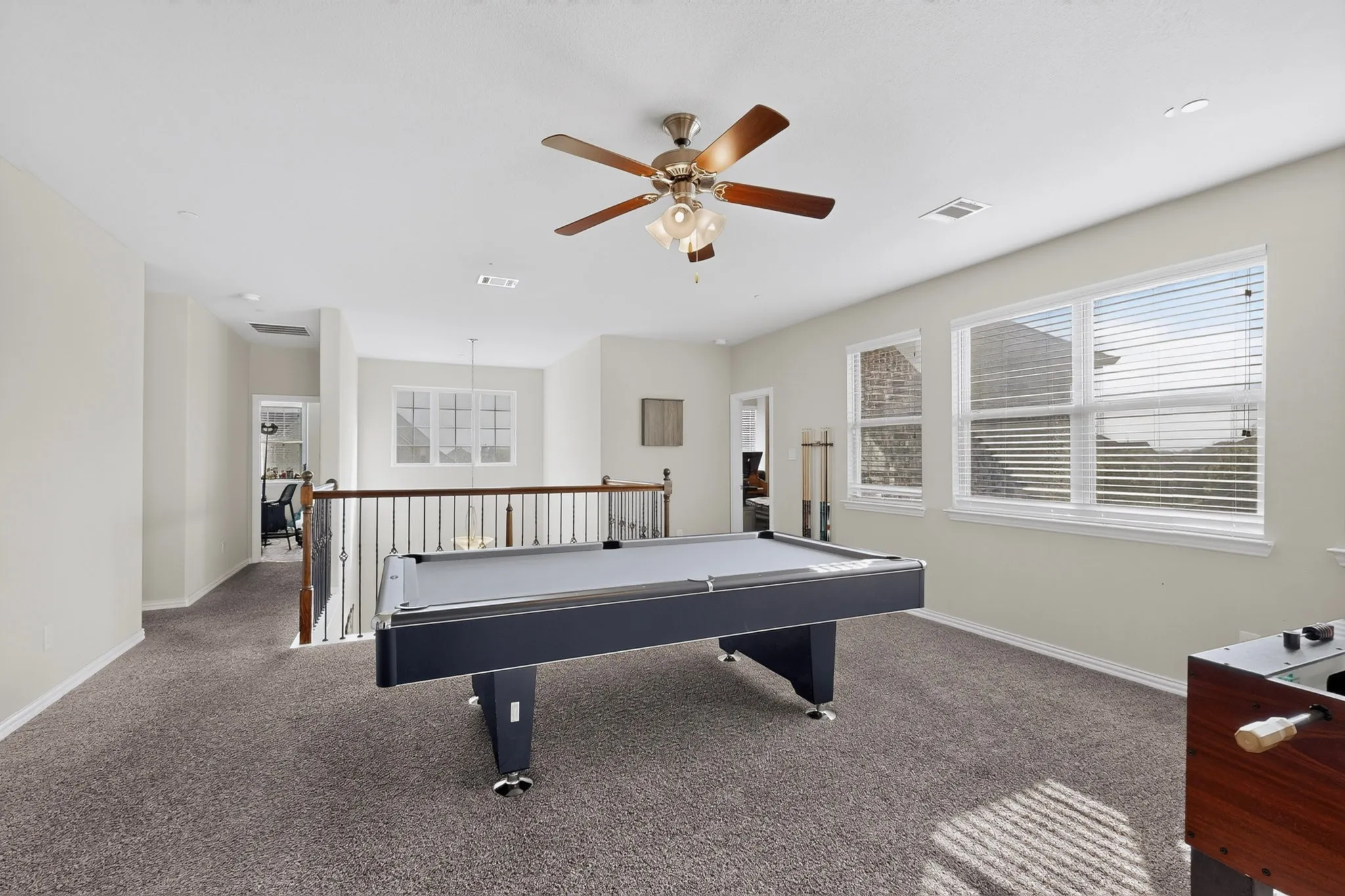 Spacious loft with neutral carpeting, multiple windows, recessed lighting, and a ceiling fan