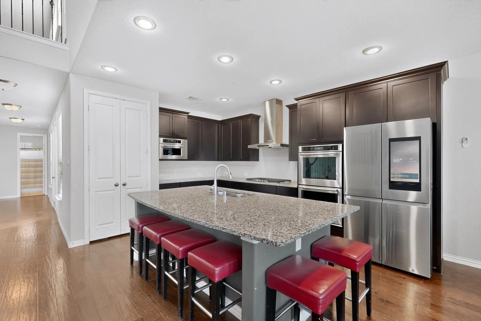 Gourmet kitchen featuring a large island with a stone countertop, dark wood-finish cabinetry, stainless steel appliances, and recessed lighting