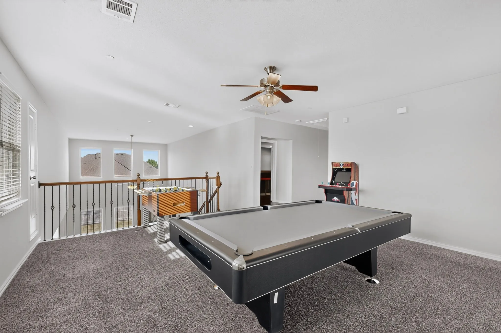 Spacious upper-level landing with plush carpet flooring, a ceiling fan, and abundant natural light from multiple windows