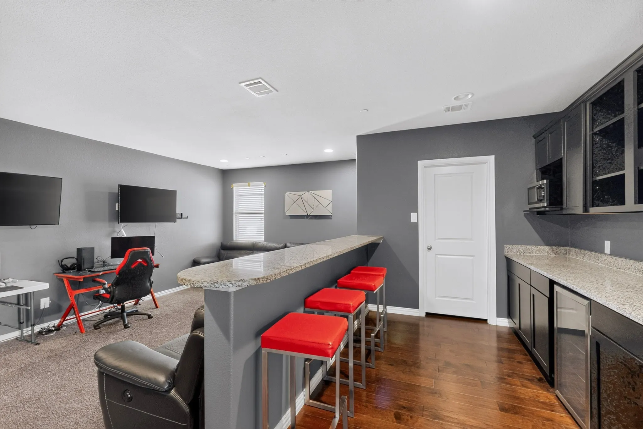 Built-in bar with stone-finish countertop, dark cabinetry, and wood-finish flooring